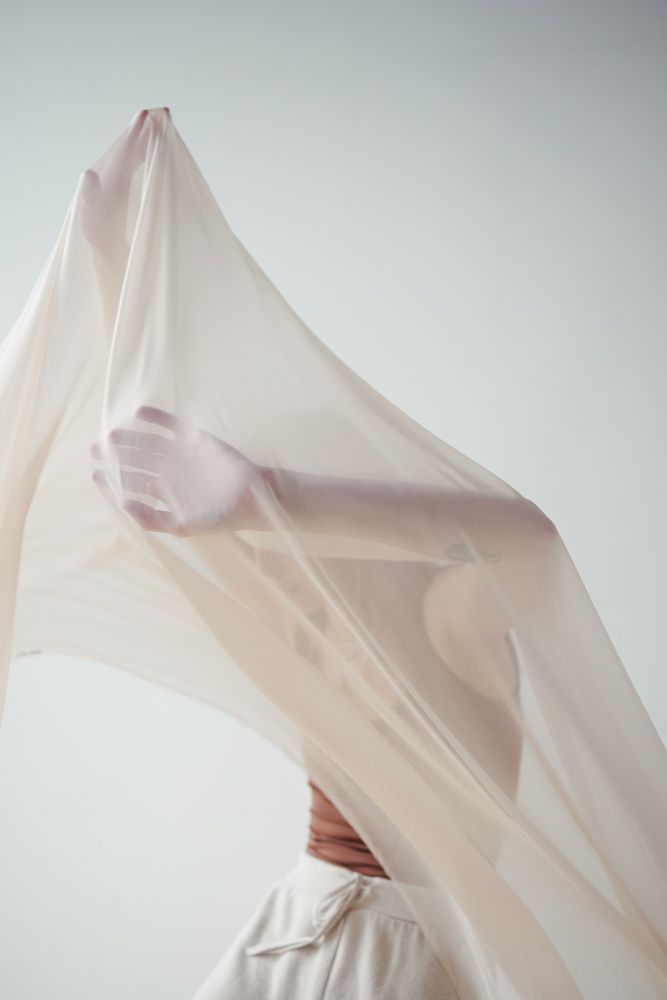 Abstract series of white fabric draped and flowing in graceful curves against a light backdrop.