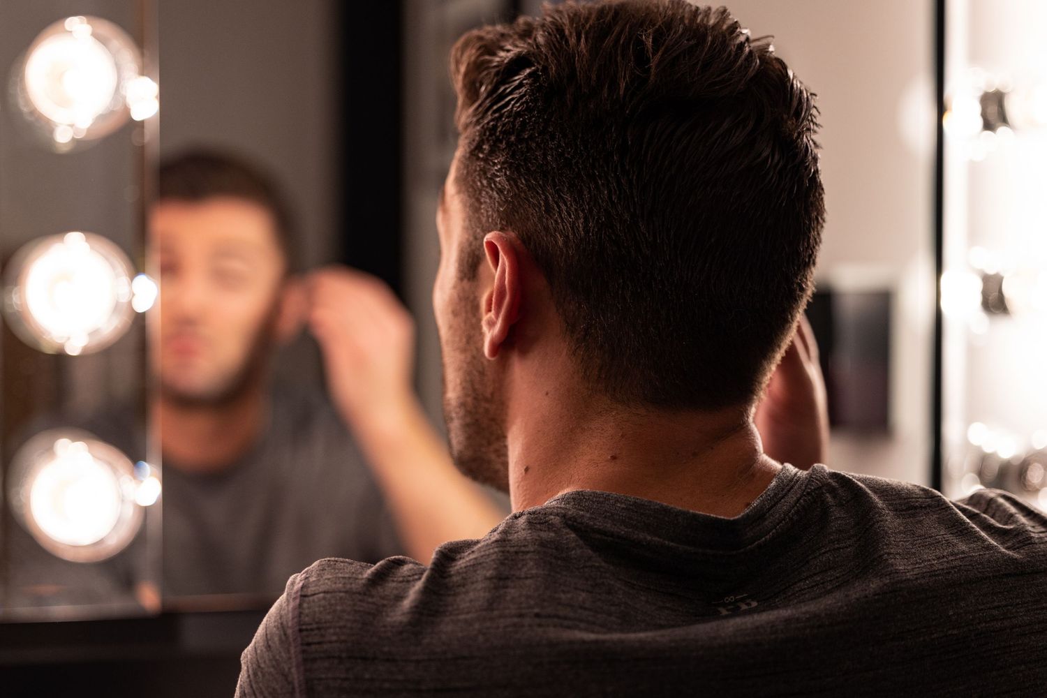 A mirror reflection shows symmetrical vanity lights glowing warmly in a dark room.