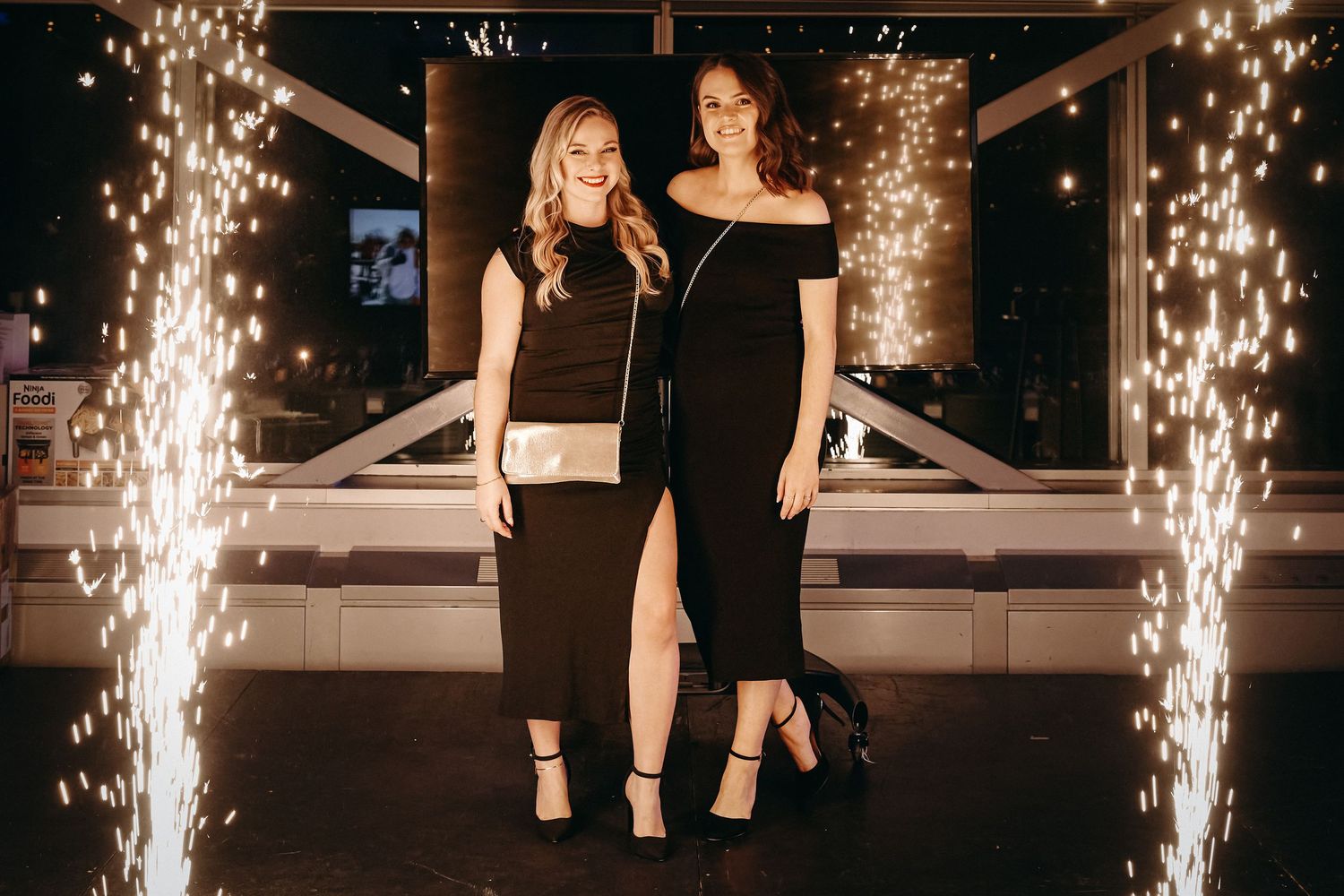 Cold sparkler fountains create dramatic lighting effects at an indoor event venue along a dark corridor.
