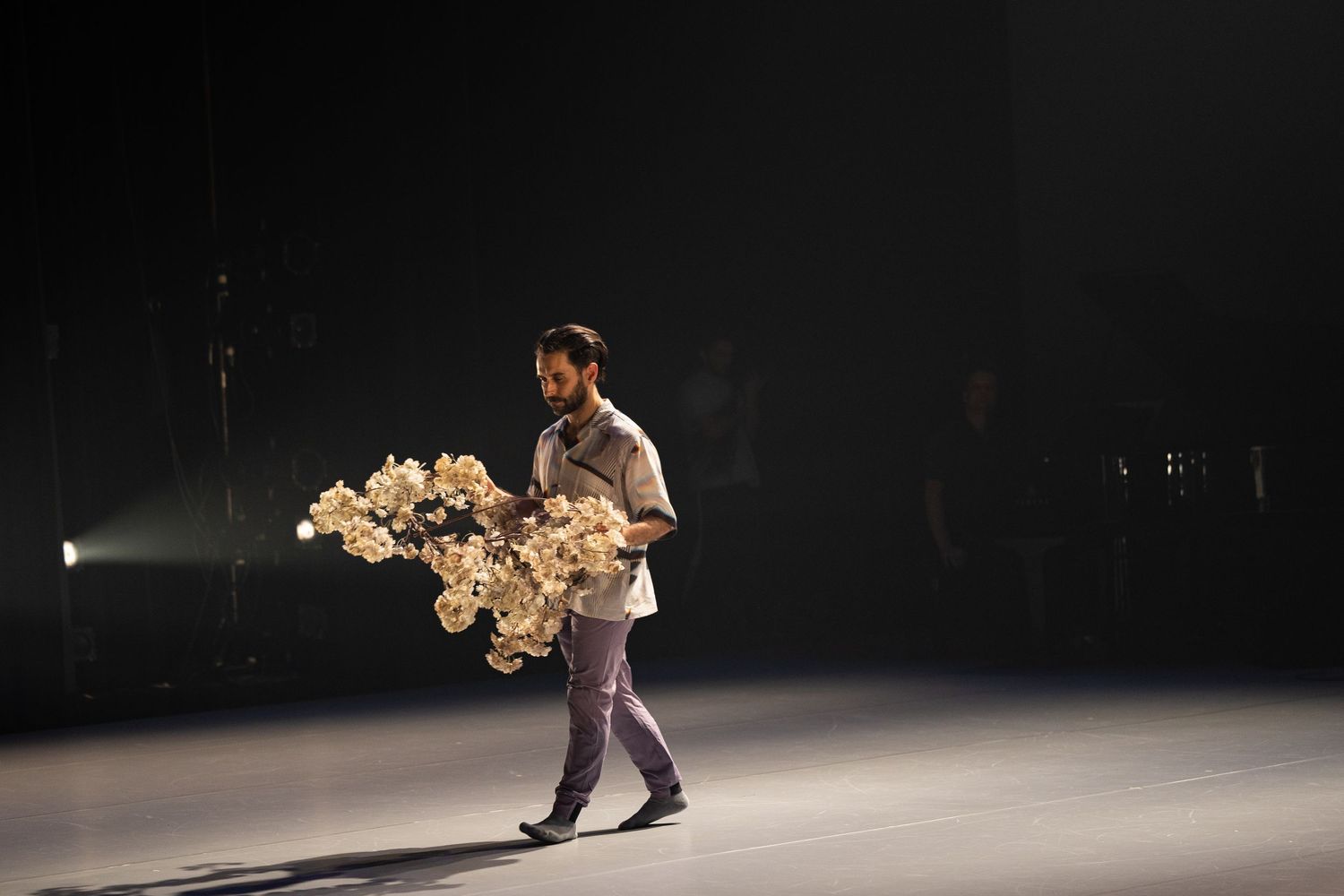 A sequence of dance movements performed by a solo artist on a dark stage with dramatic lighting.