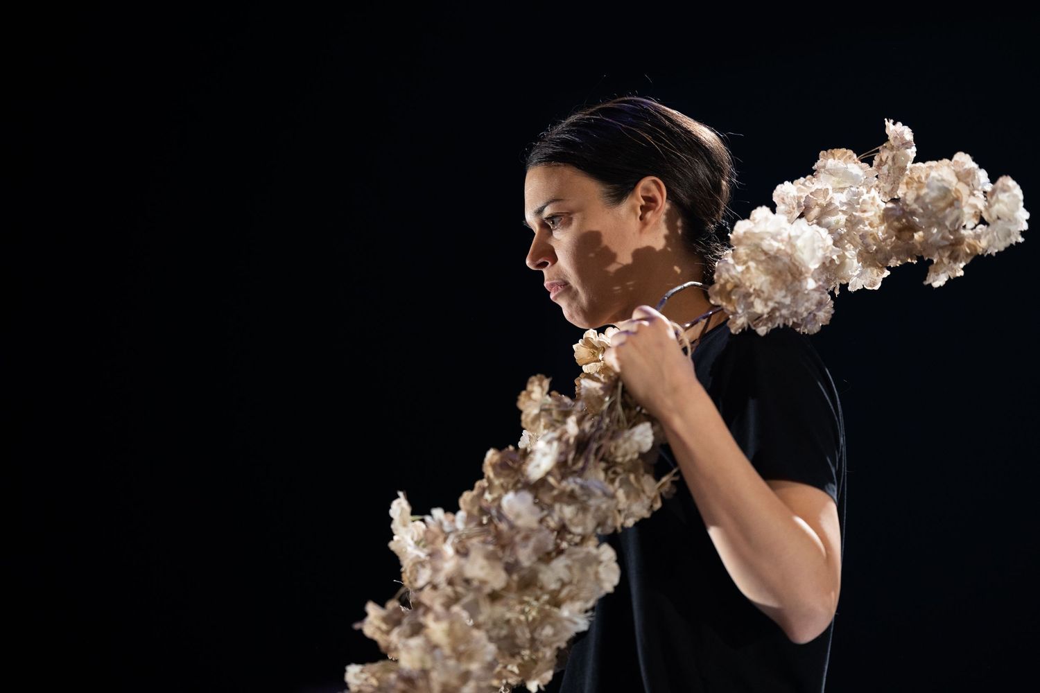 A person in a black shirt releases a billowing trail of white smoke while posing against a dark background.