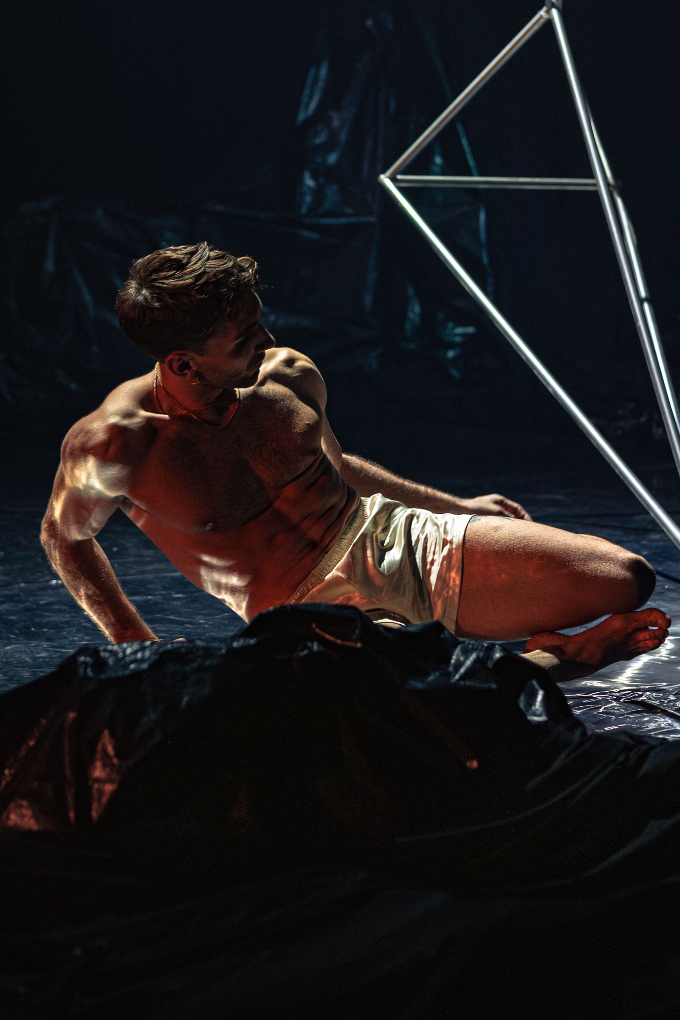 Dramatic sequence of silhouettes showing a person doing a rock climbing move in dim lighting against a dark background.