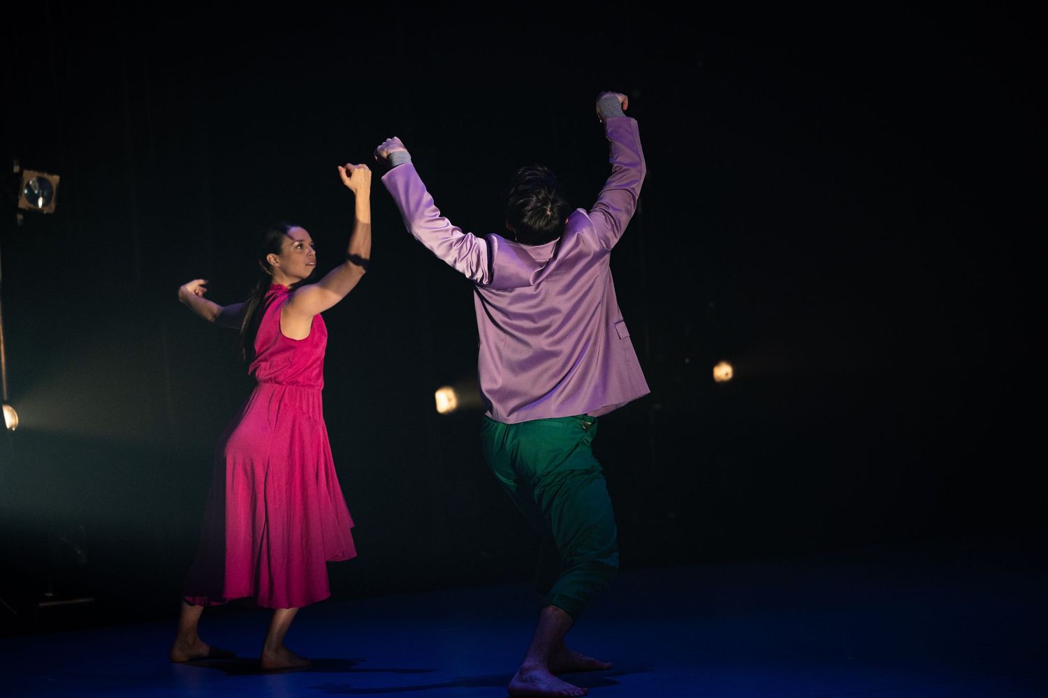 Dancers perform an energetic contemporary dance routine in flowing costumes under dramatic stage lighting.