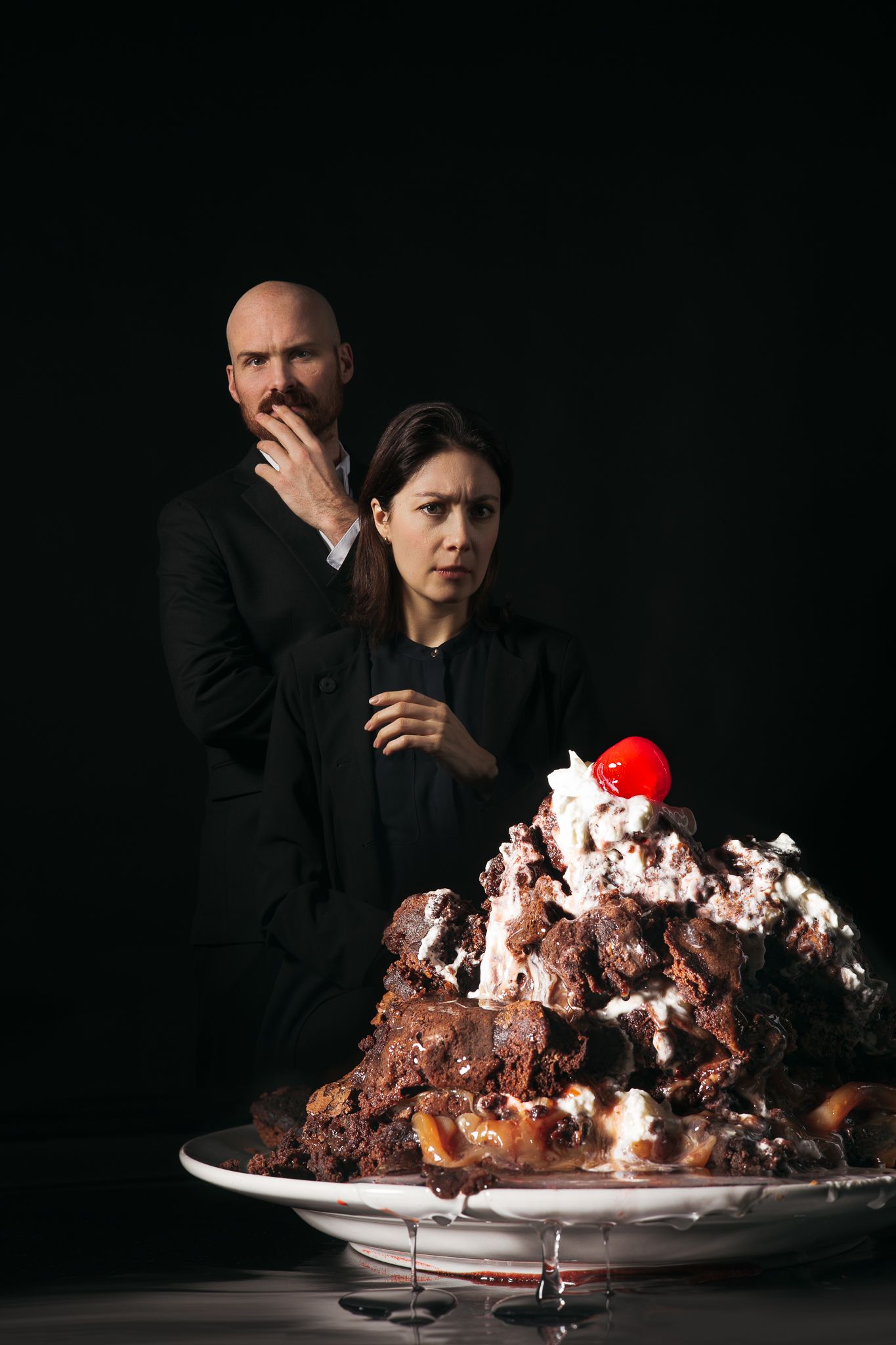 Five dramatic sequential shots of a chocolate dessert being set ablaze and consumed on a white plate against dark background.