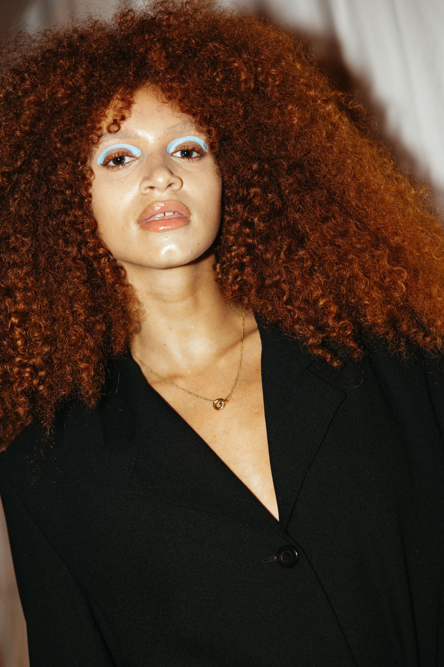 Portrait series featuring curly natural hair and black clothing against a light-colored background.