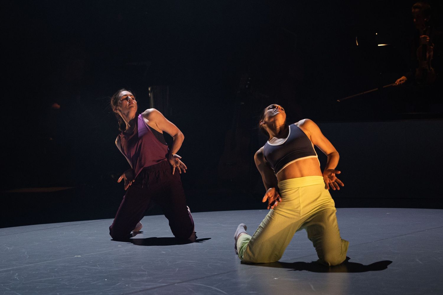 Dancers performing choreographed sequences on a dark stage with dramatic lighting.