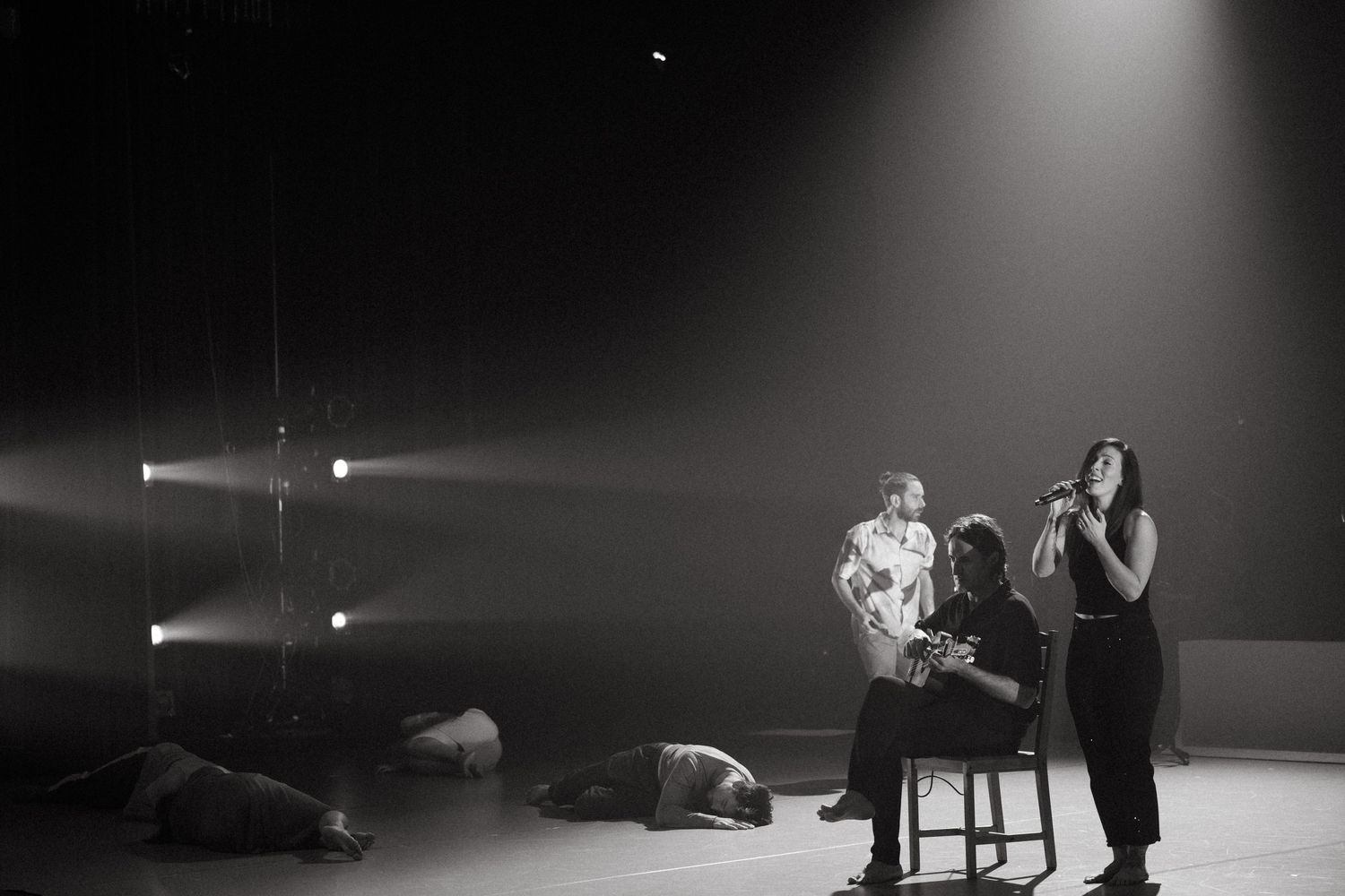 Contemporary dancers perform a dramatic sequence across a dimly lit stage, showcasing powerful movements and fluid gestures.