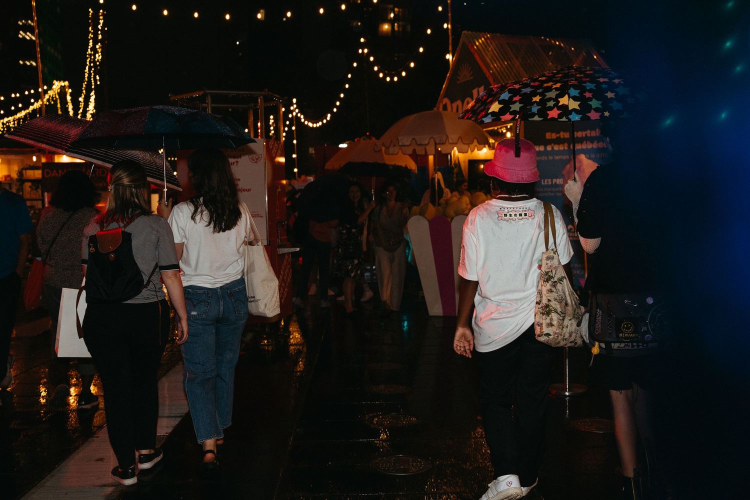 People gathering at a dimly lit indoor venue with string lights and decorative lighting creating a warm ambiance.
