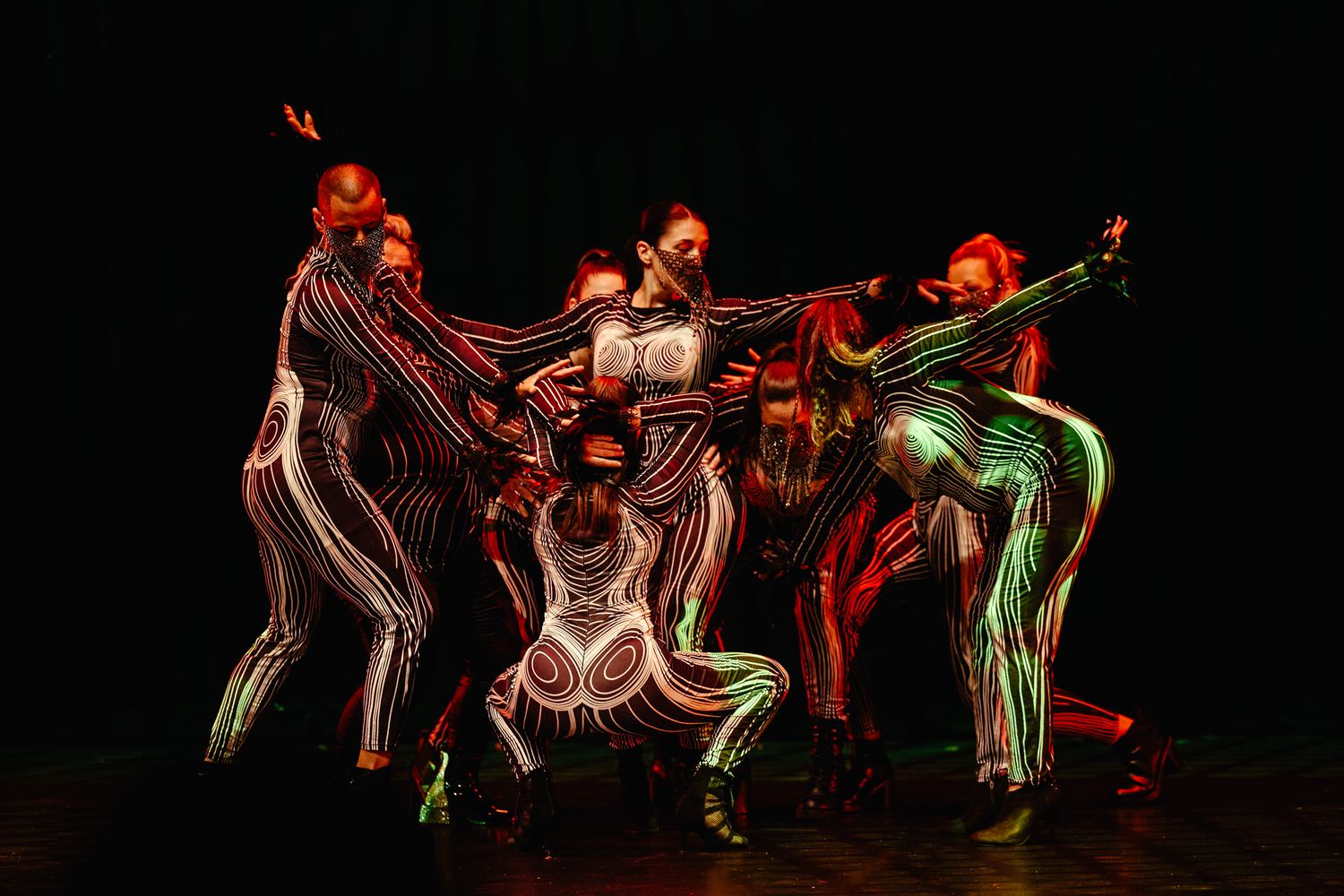 Long exposure photograph shows dancers creating light trails with LED lights against dark background.