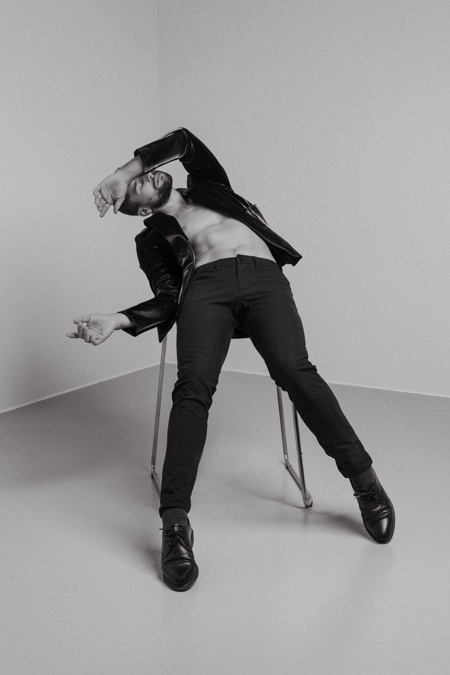 A sequence of five black and white photos shows a figure in dark clothing collapsing onto a white floor in dramatic poses.