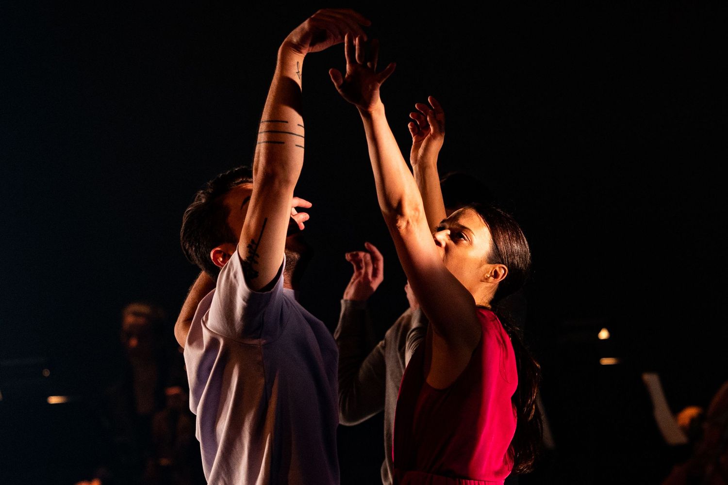 Two athletes leap high to grab a basketball during an intense nighttime game or practice session.