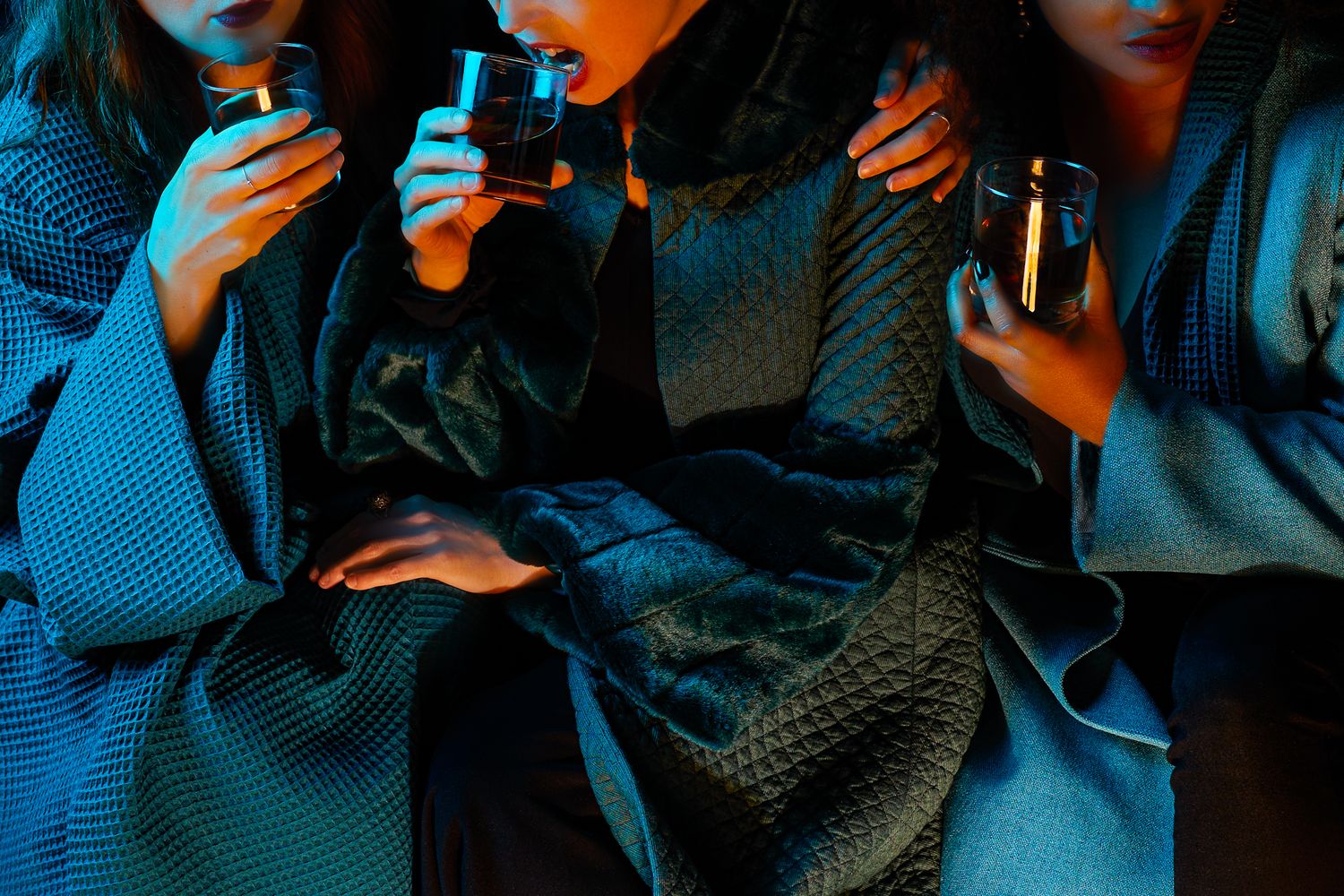 Group of friends enjoying drinks at a dimly lit table with blue lighting, creating a cozy nightlife atmosphere.