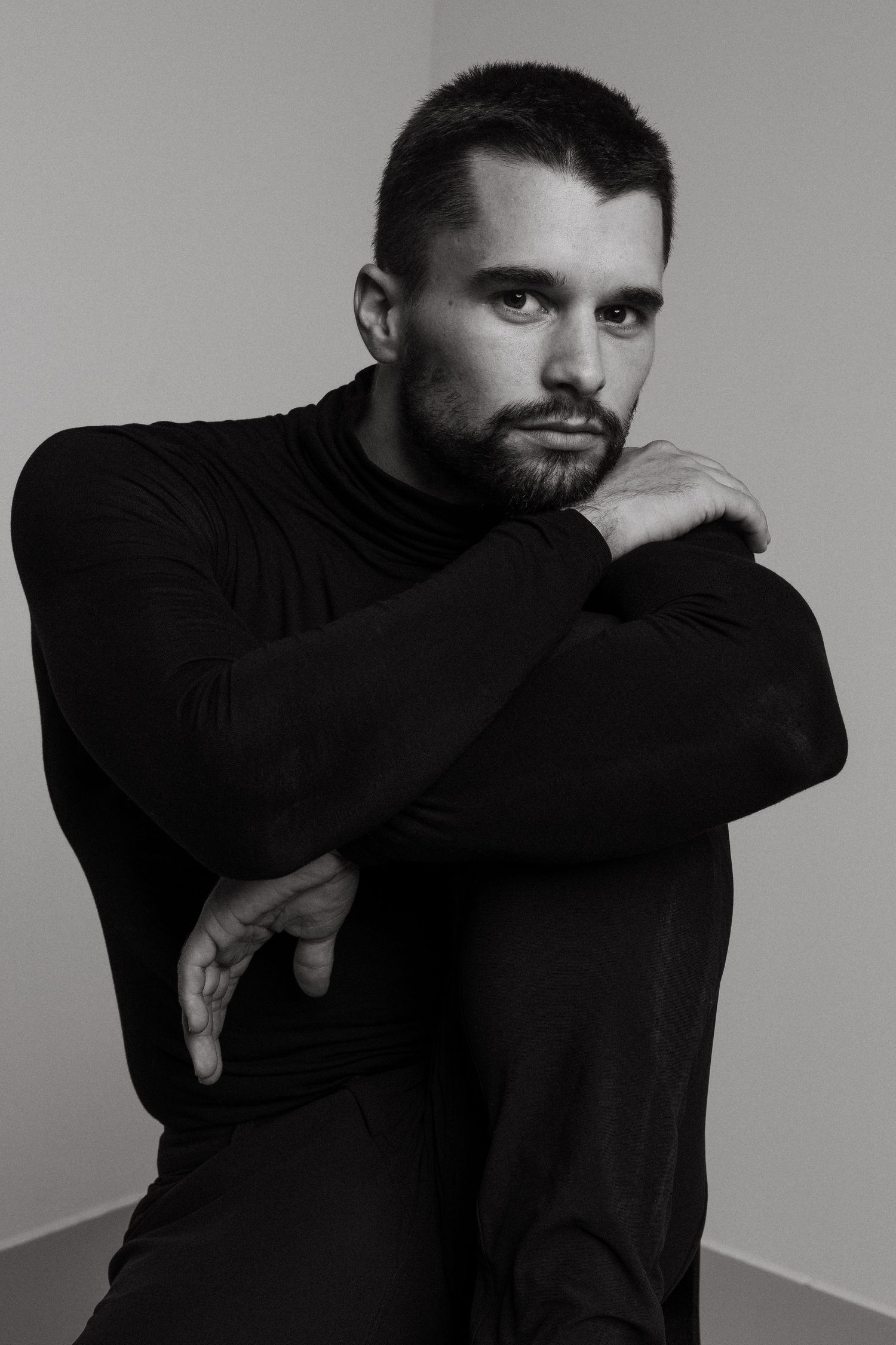 A black and white photo series showing someone in a dark hoodie making dramatic poses against a plain background.