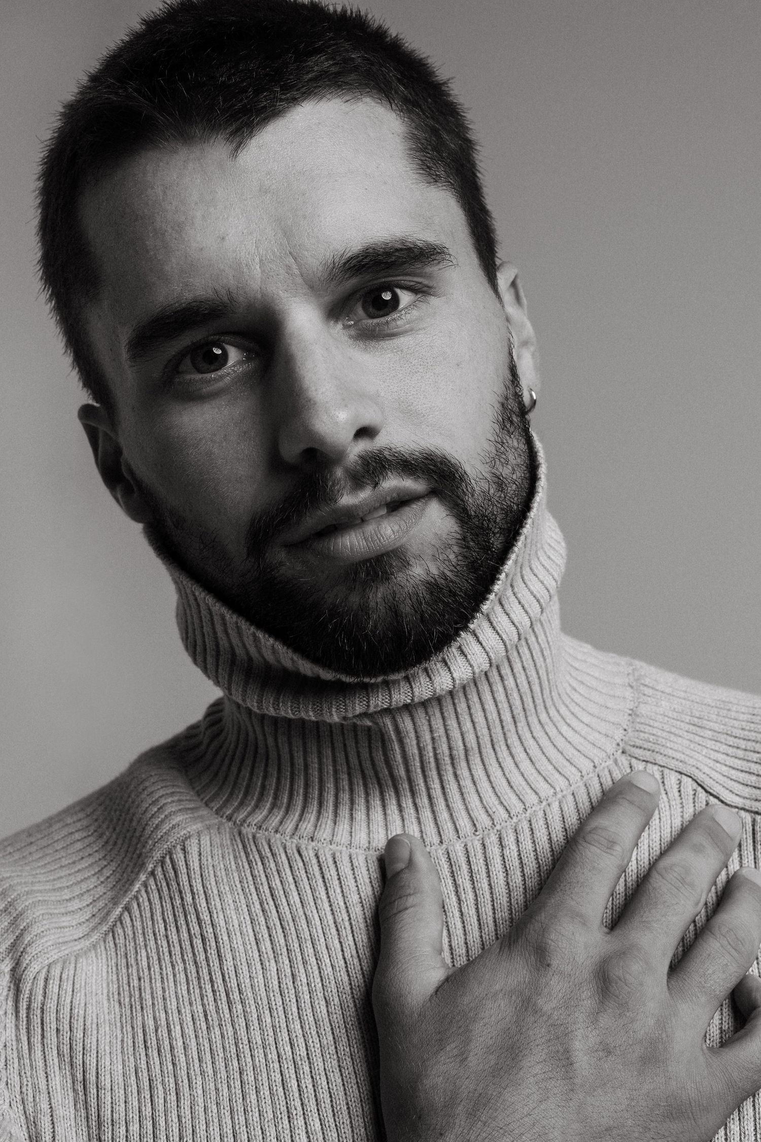 A black and white portrait series showing someone in a turtleneck sweater making different expressive poses.