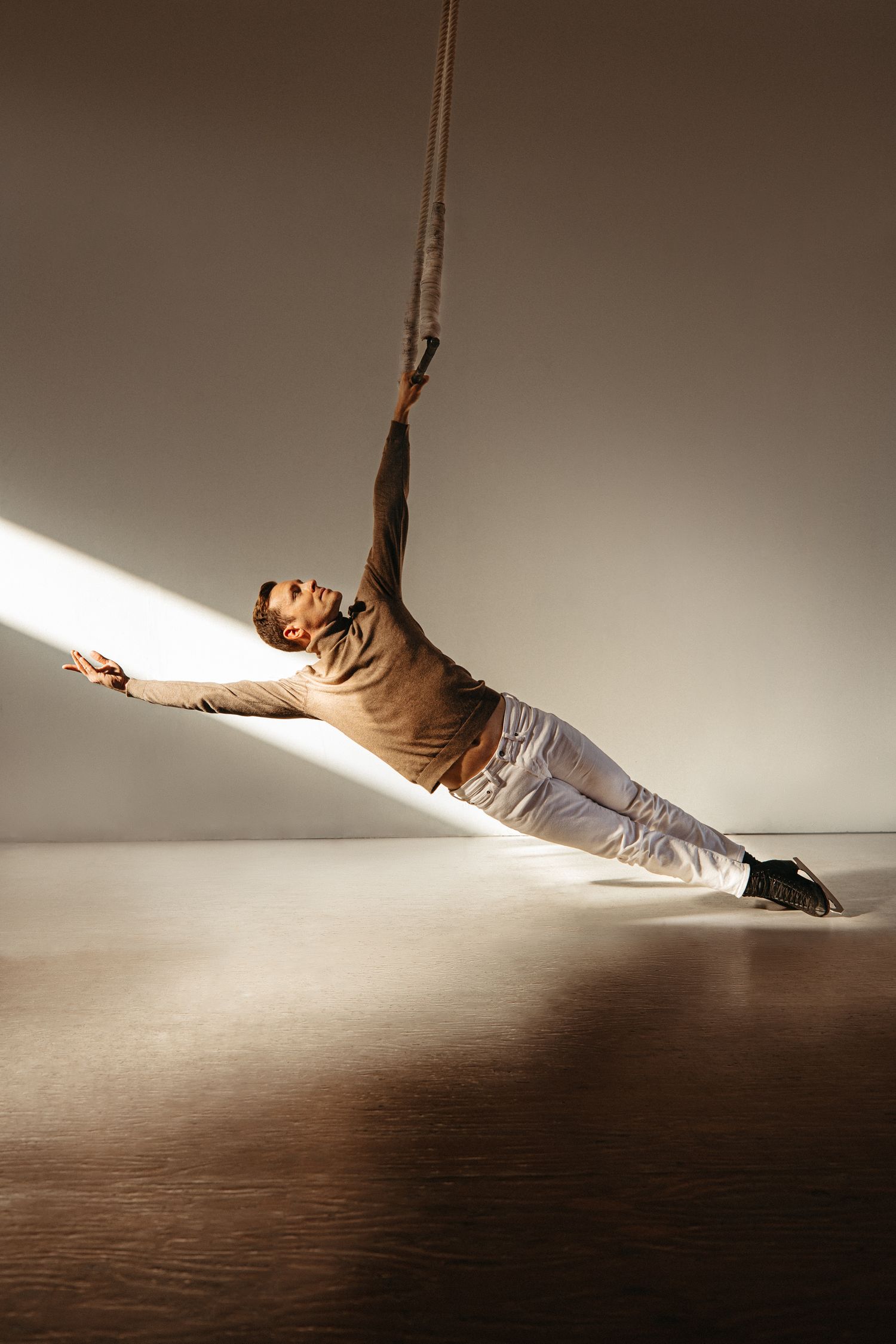 A dramatic dance sequence showing a performer suspended in mid-air creating fluid movements against a shadowy backdrop.