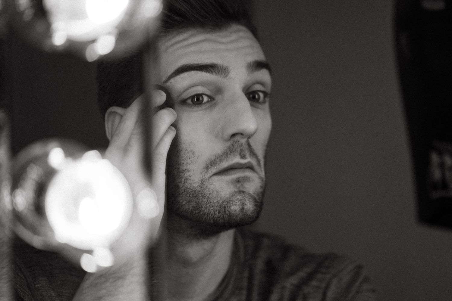 A black and white portrait photo with dramatic lighting and bokeh effects in the background.