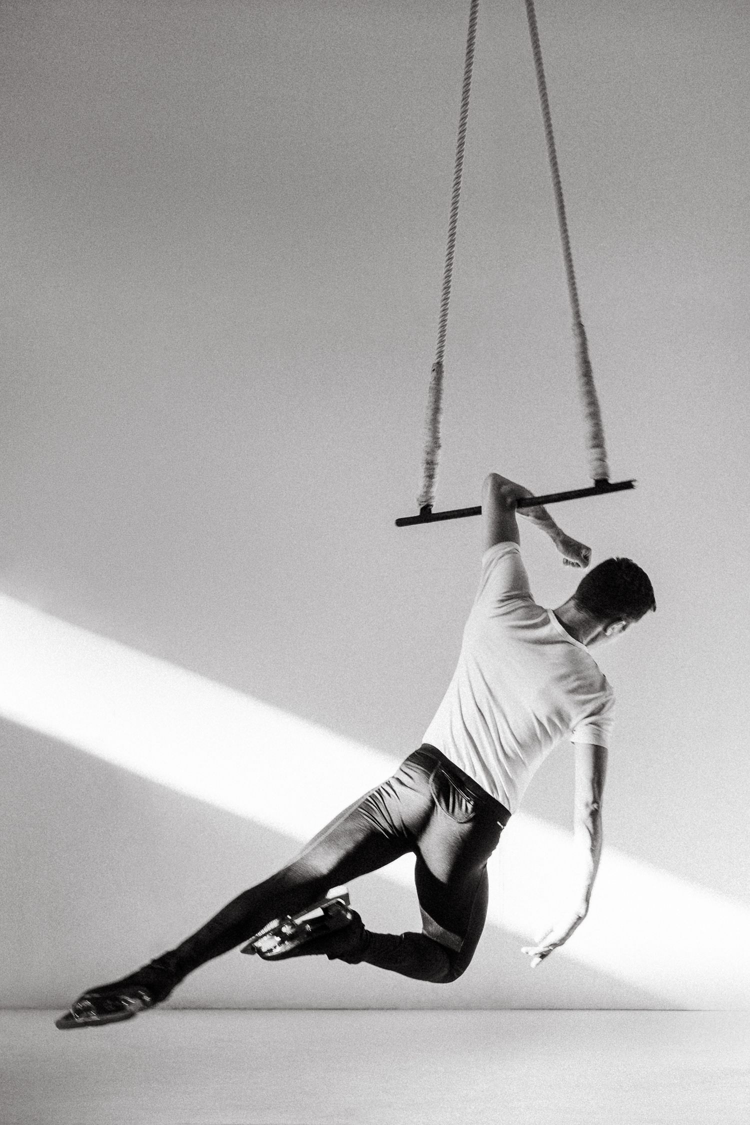 A minimalist black and white photo sequence showing a dance movement with ropes against a stark white background.