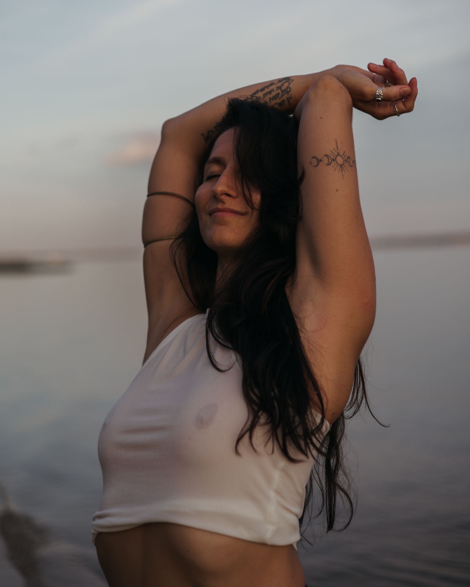 A figure captured at sunset in a series of moody, artistic dance-like poses wearing a light colored tank top.