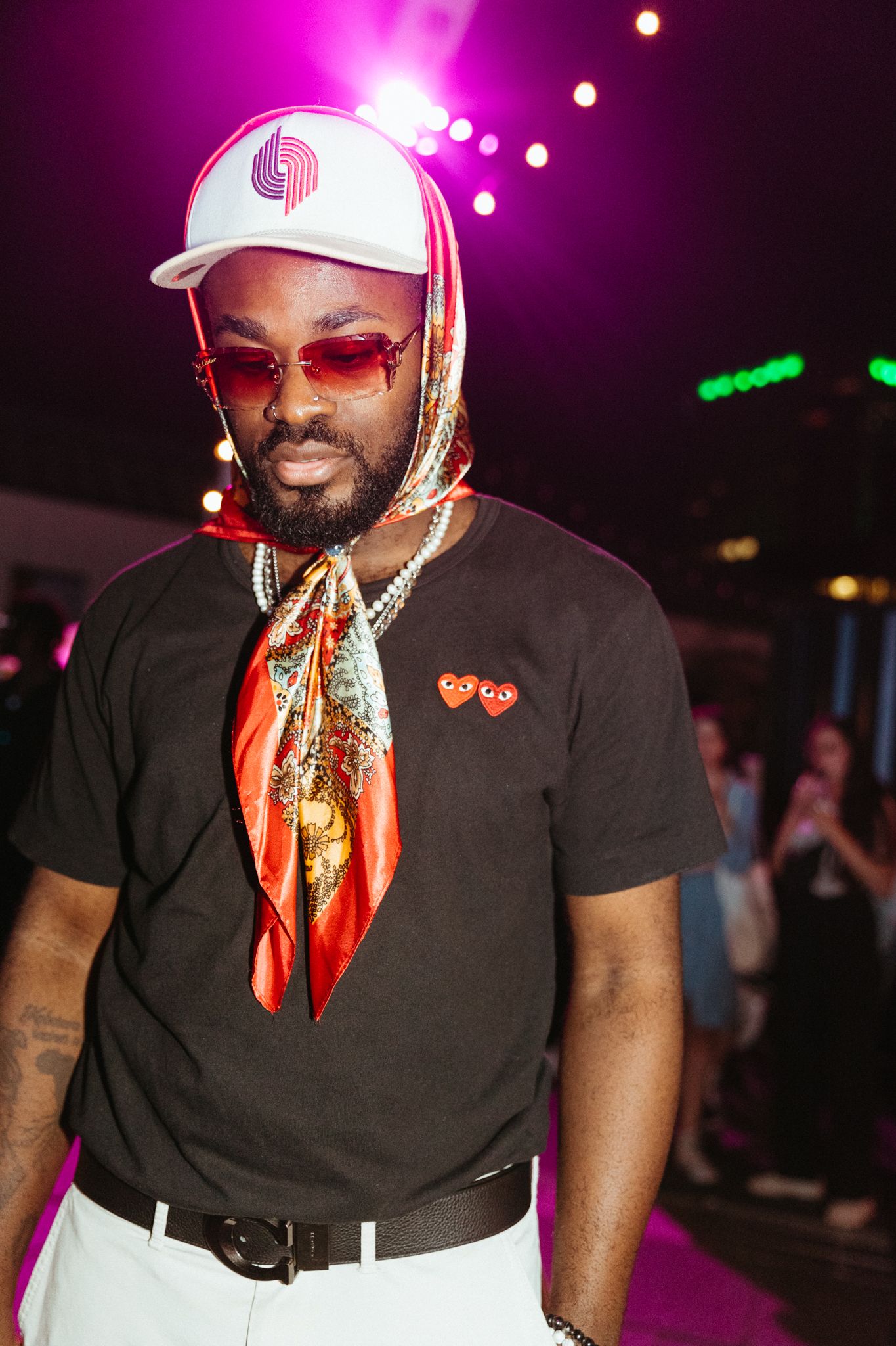 Party performer wearing black t-shirt and sunglasses strikes poses in colorful nightclub lighting.