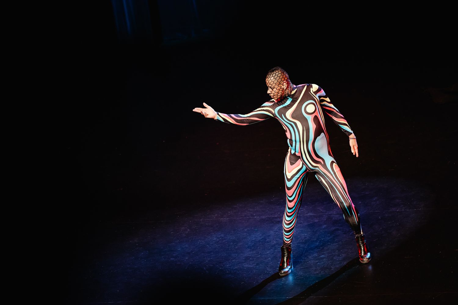 A modern dance performance featuring multiple dancers in black and white striped costumes on a dark stage.