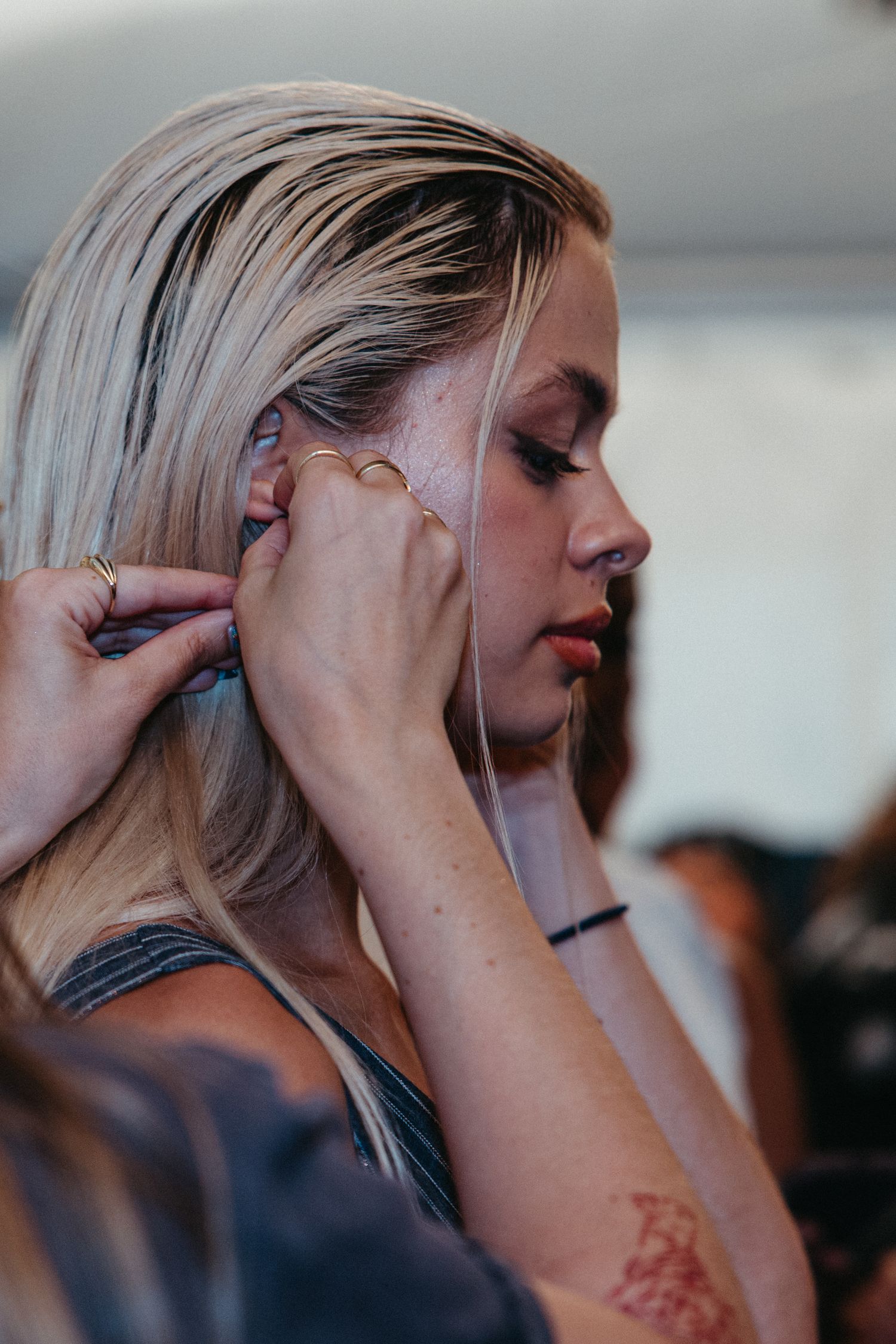 A series of side profile shots showing a woman with platinum blonde hair touching her temple and neck.