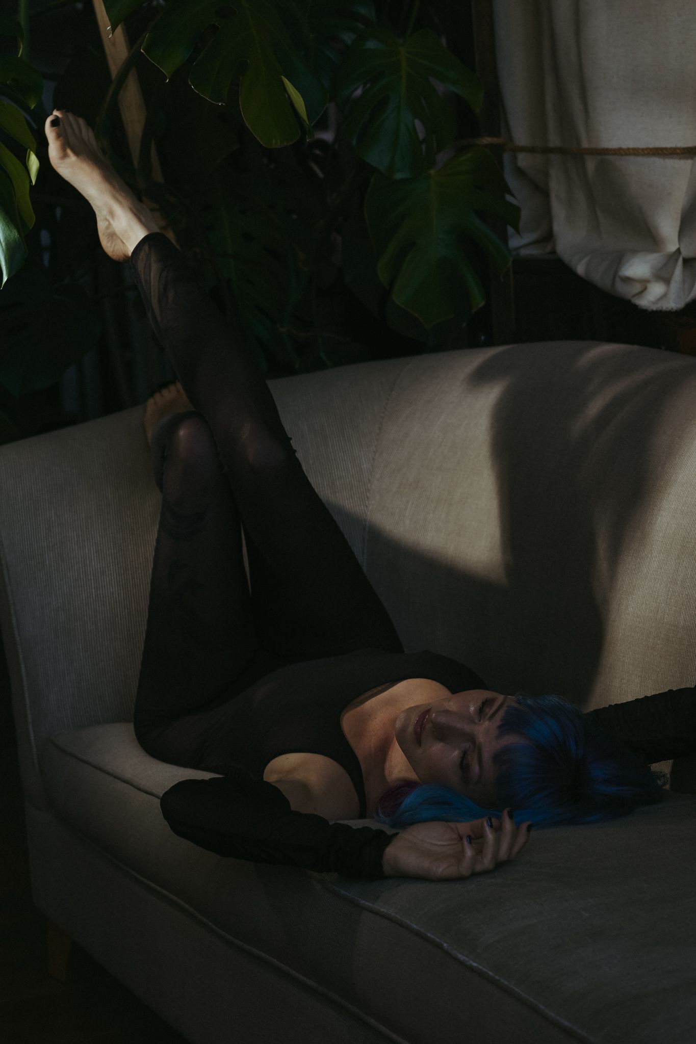 A series of shadowy photographs showing a figure sleeping or resting on a dark couch in low lighting conditions.