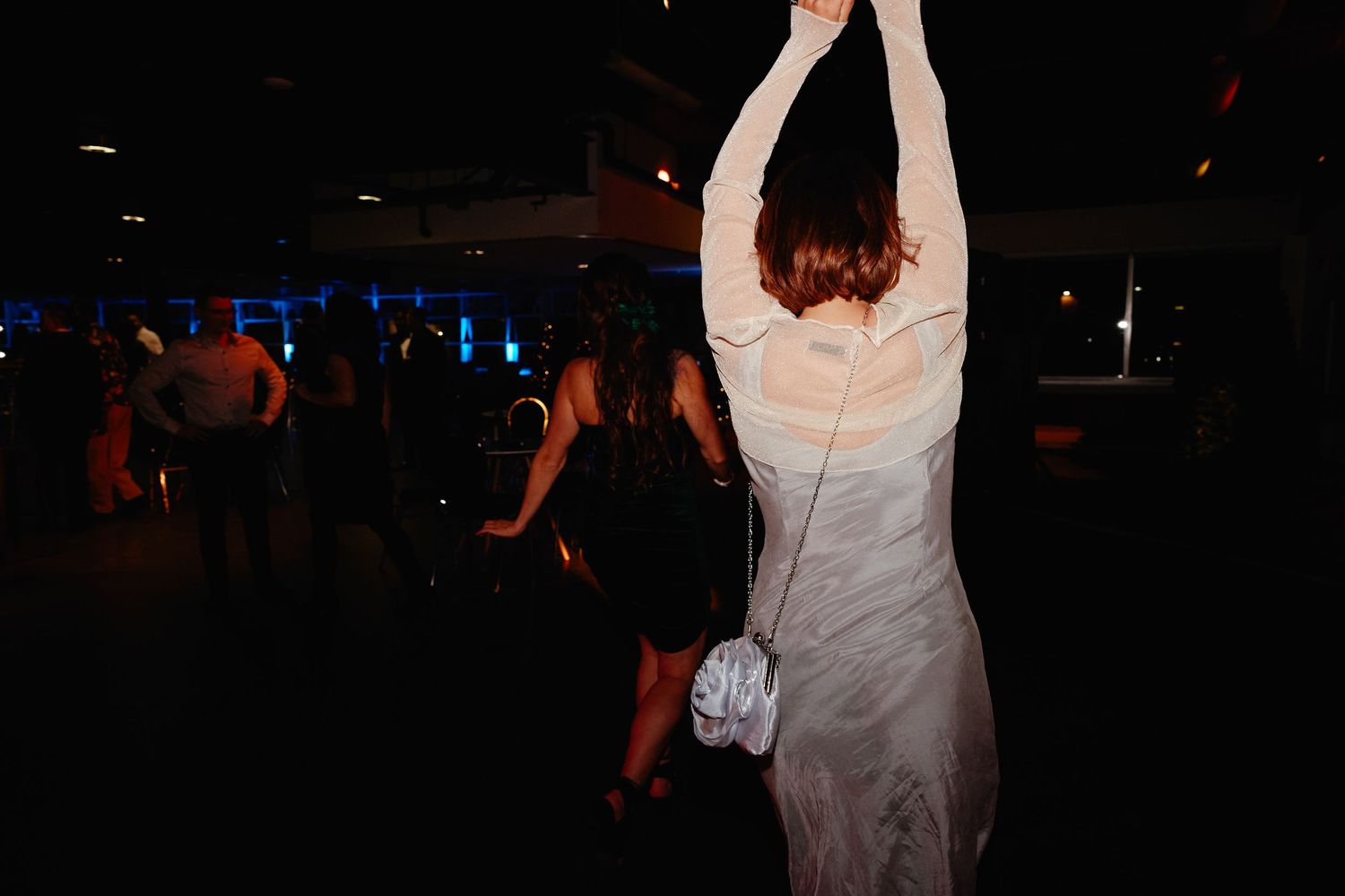 A group of people dancing and enjoying themselves at a nightclub with blue lighting and dark atmosphere.