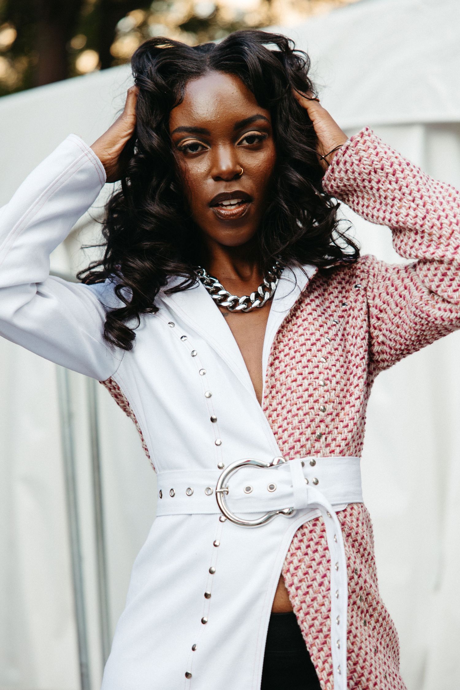Fashion model poses in a split-design dress featuring contrasting white and red polka dot pattern with button details.