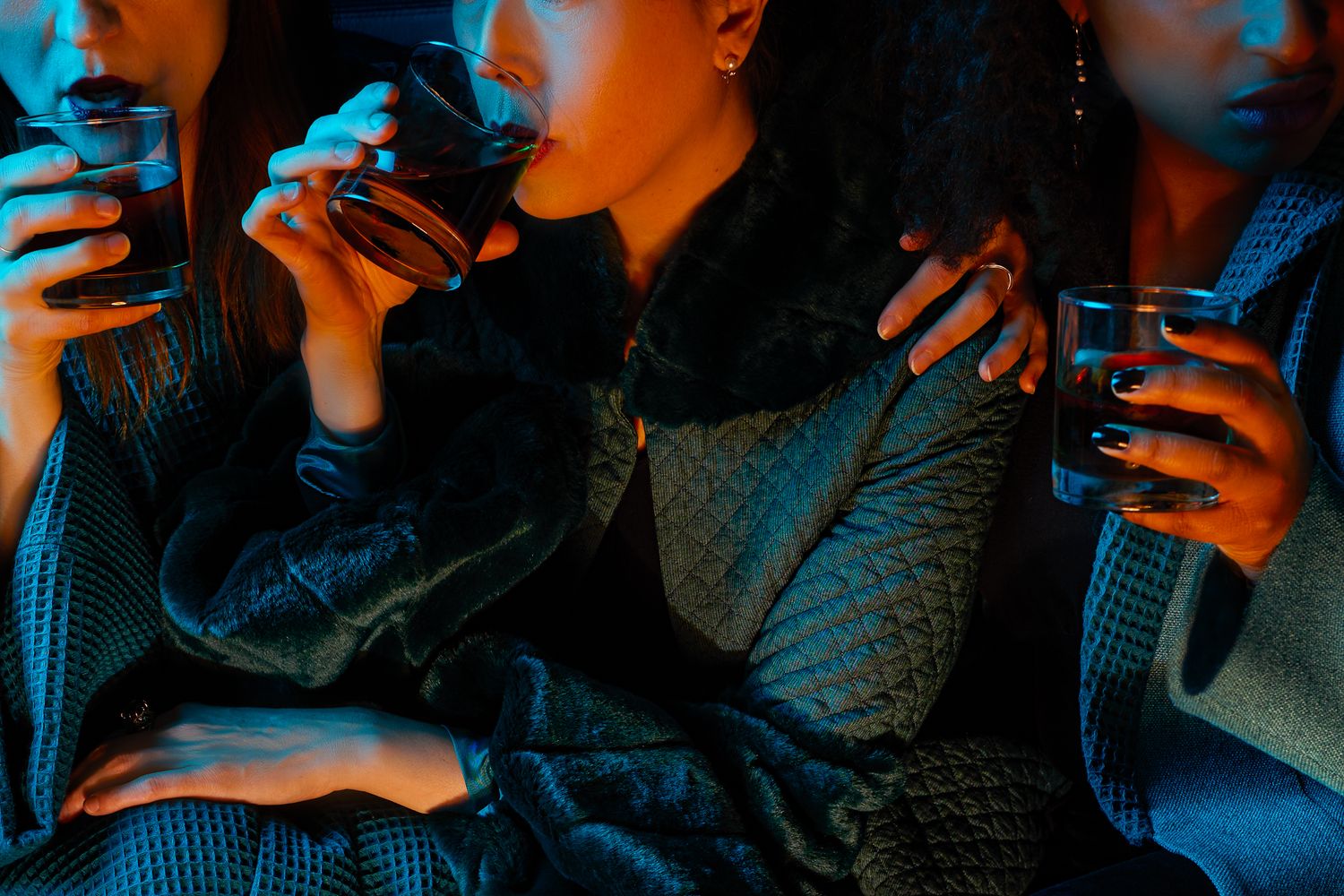 Group of people using smartphones illuminated by blue and orange lighting in a dark setting.