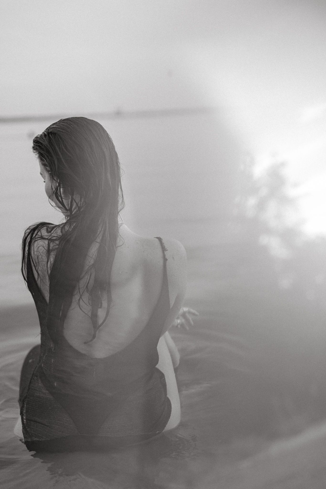 Black and white artistic photo of a silhouette sitting peacefully in water.