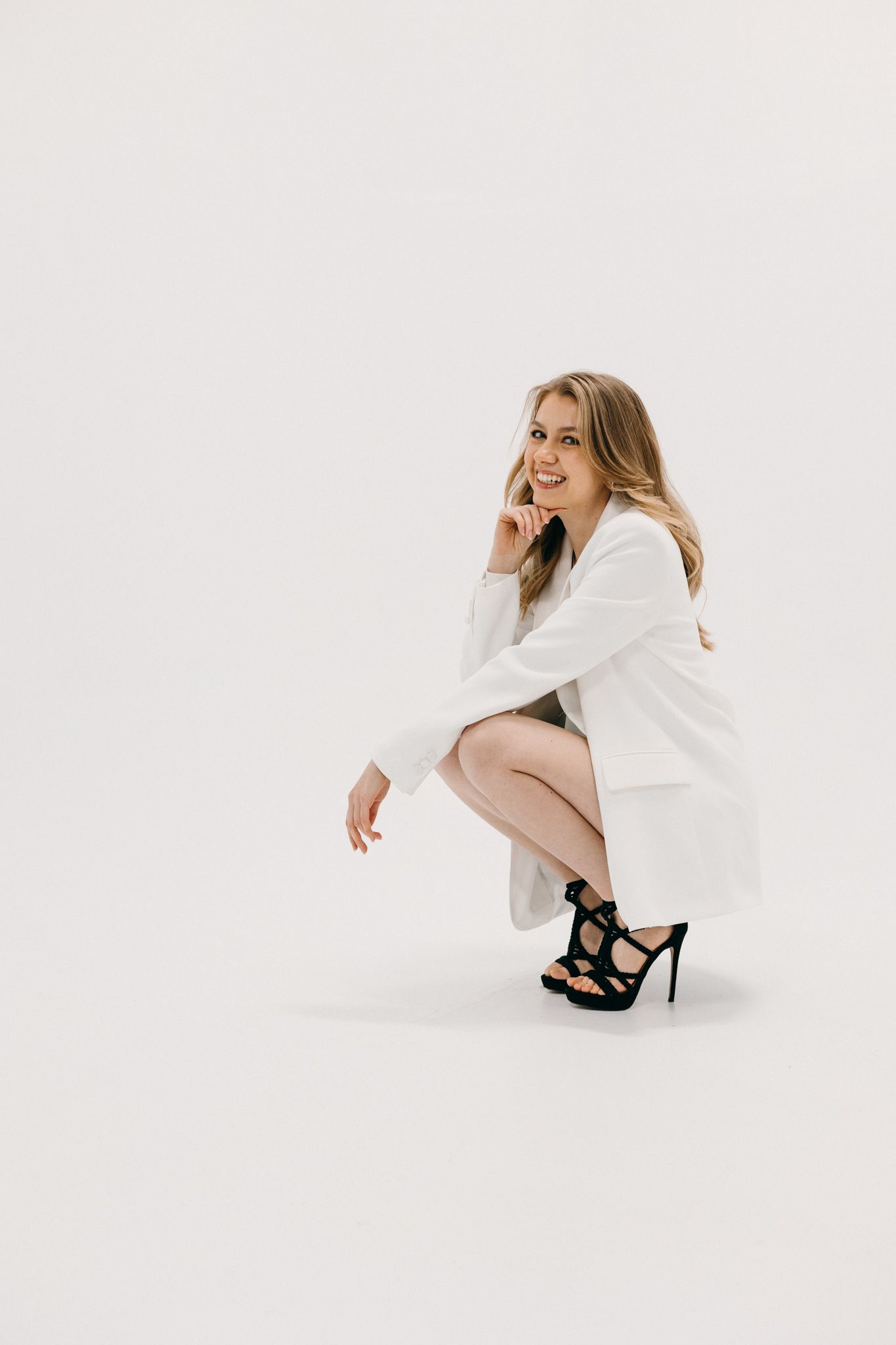 Elegant figure in white flowing top and beige pants strikes dynamic poses against minimalist white studio background.