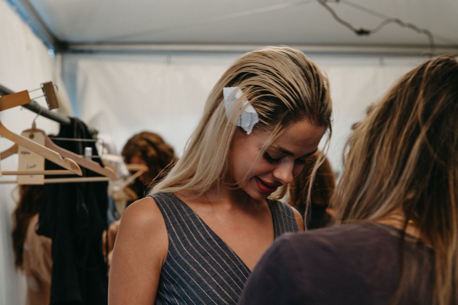 Behind the scenes at fashion event showing people interacting in a dressing area.