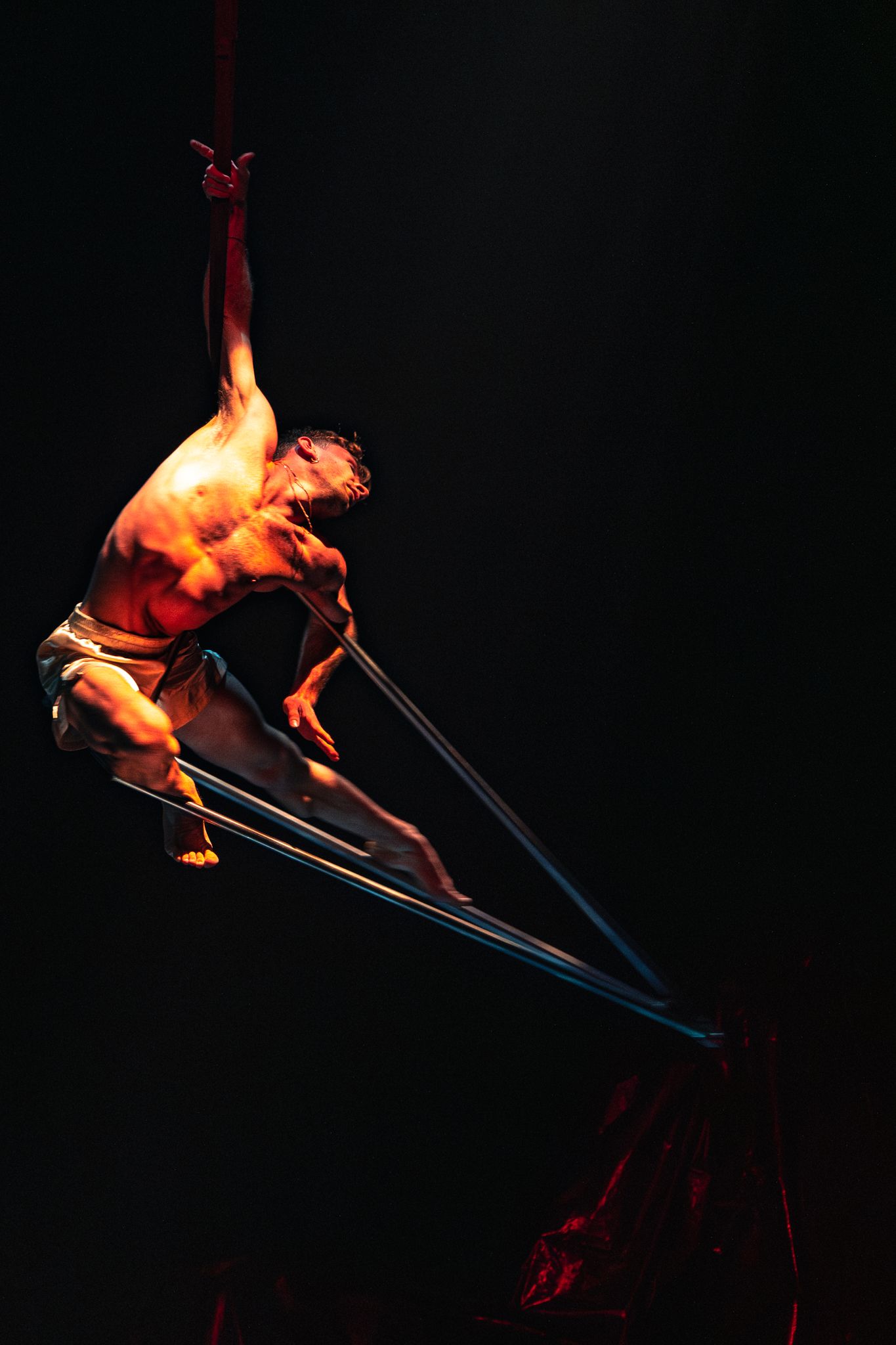Dramatic performance sequence of acrobatic routine showing athletic figure jumping with graceful form in dark lighting.