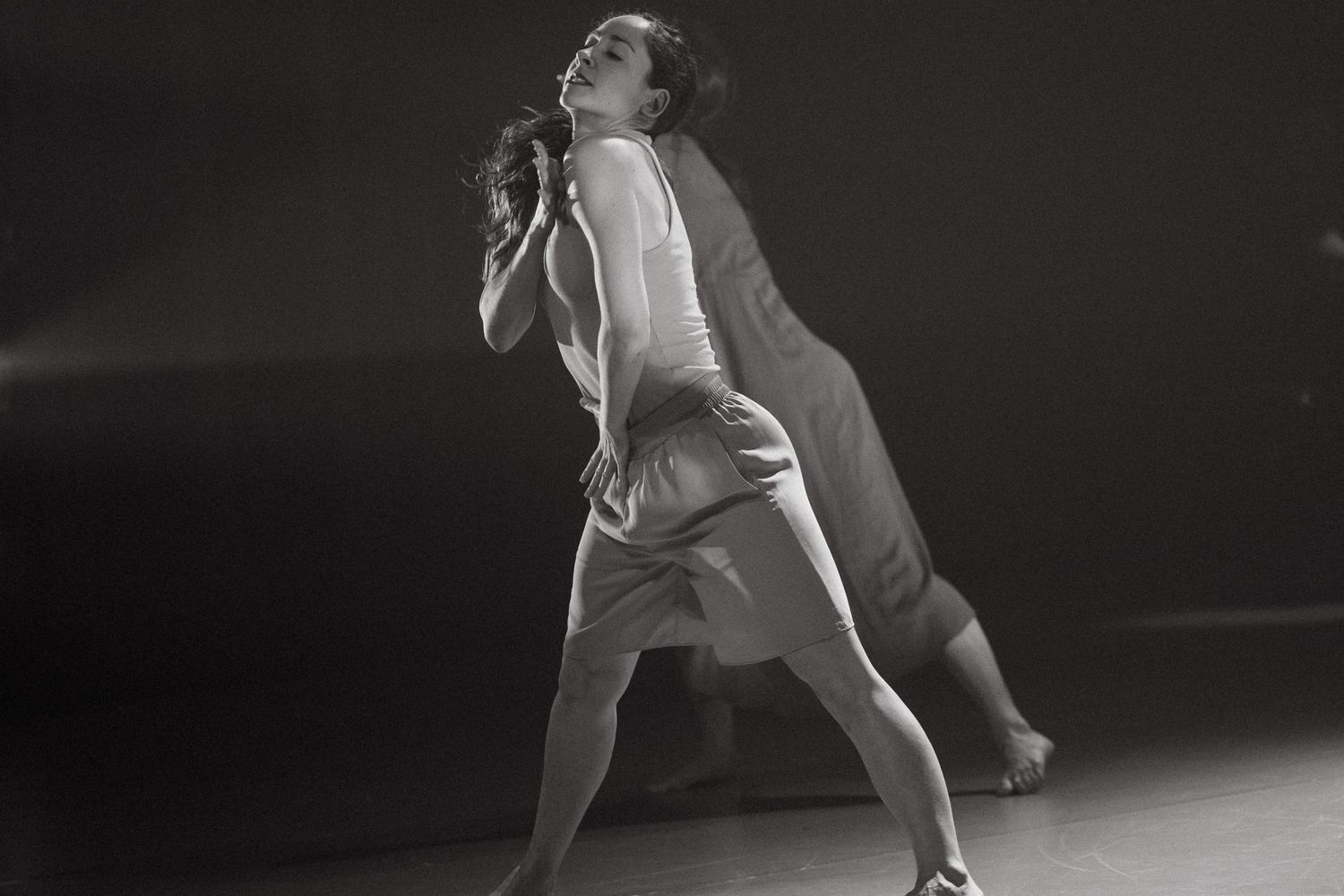 A black and white series of photos showing a dancer in elegant motion performing modern ballet movements on stage.