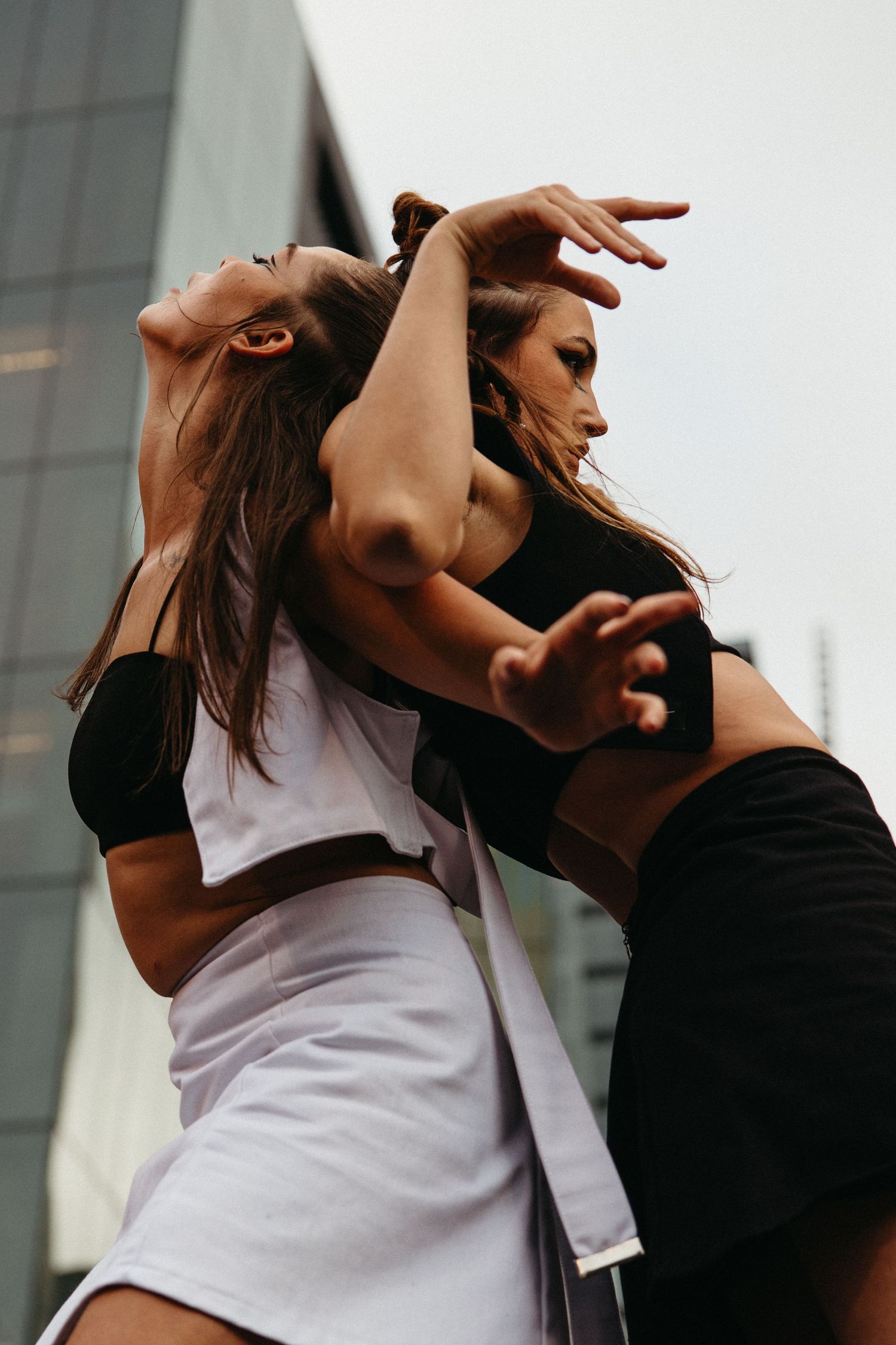 A couple dancing expressively together, with dramatic movements against an urban backdrop at dusk.
