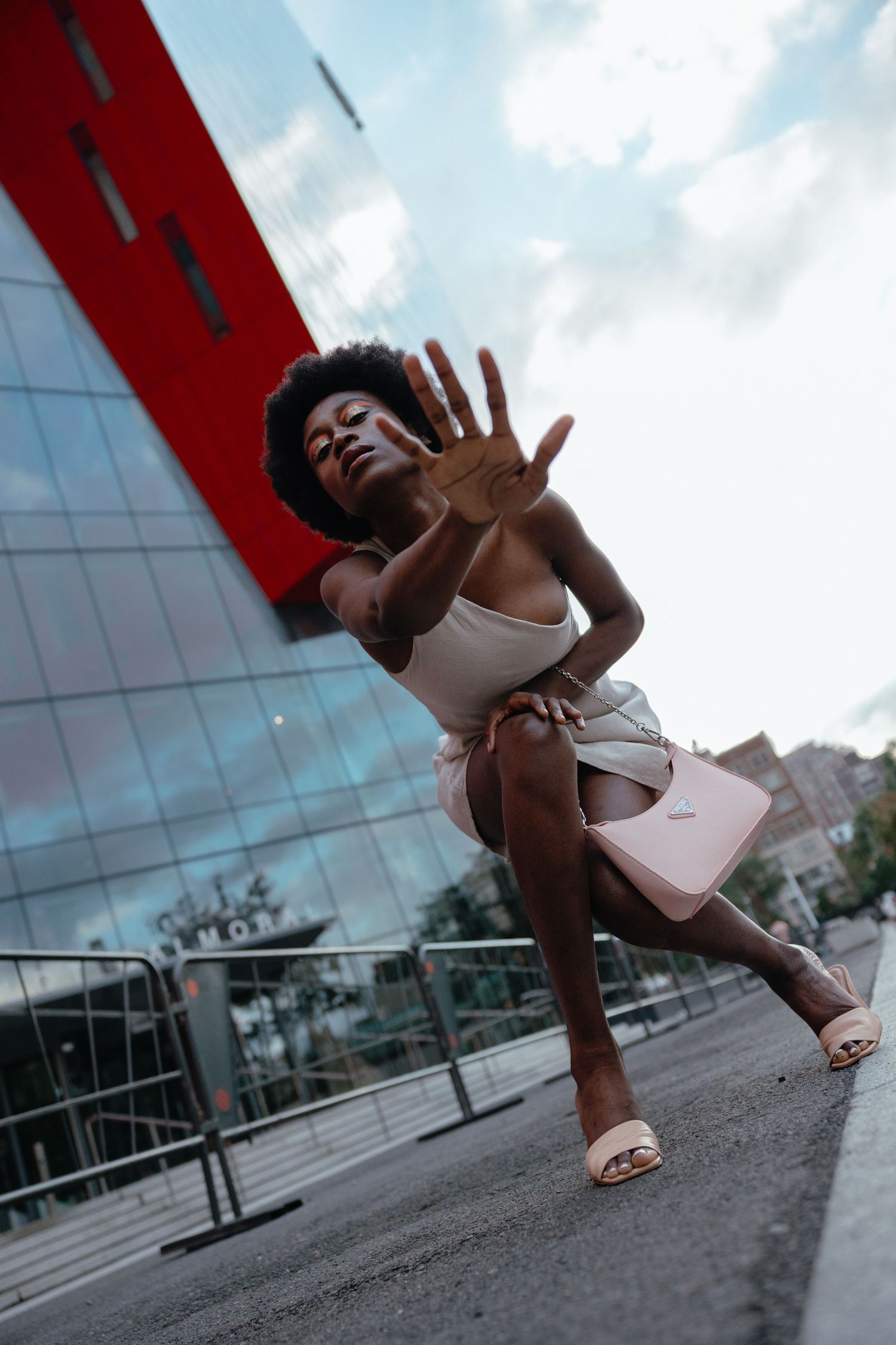Dynamic street photography of a dancer in casual attire striking an expressive pose against a modern building exterior.