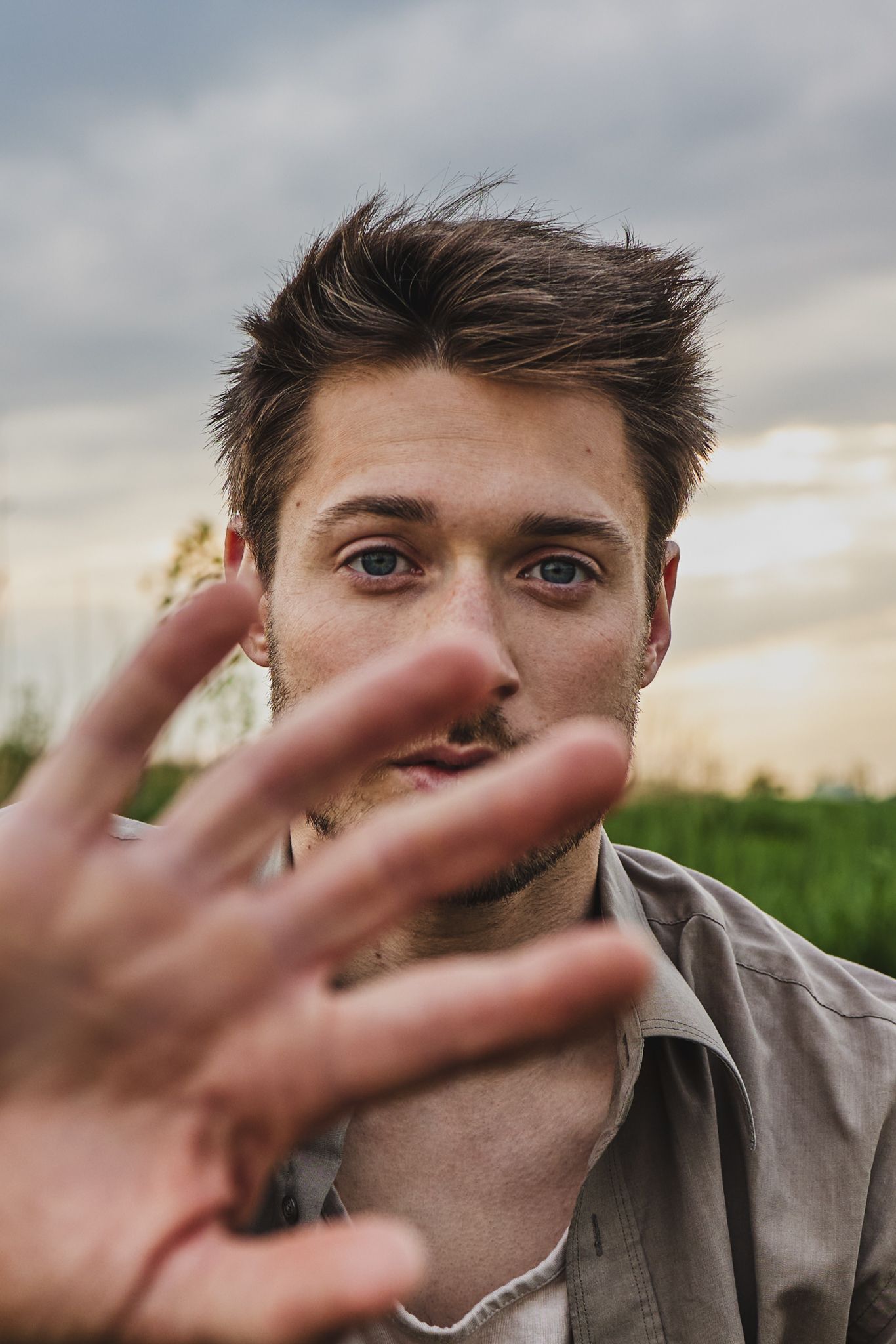 A hand reaching out to block the camera view in a series of sequential photos against a cloudy sky background.