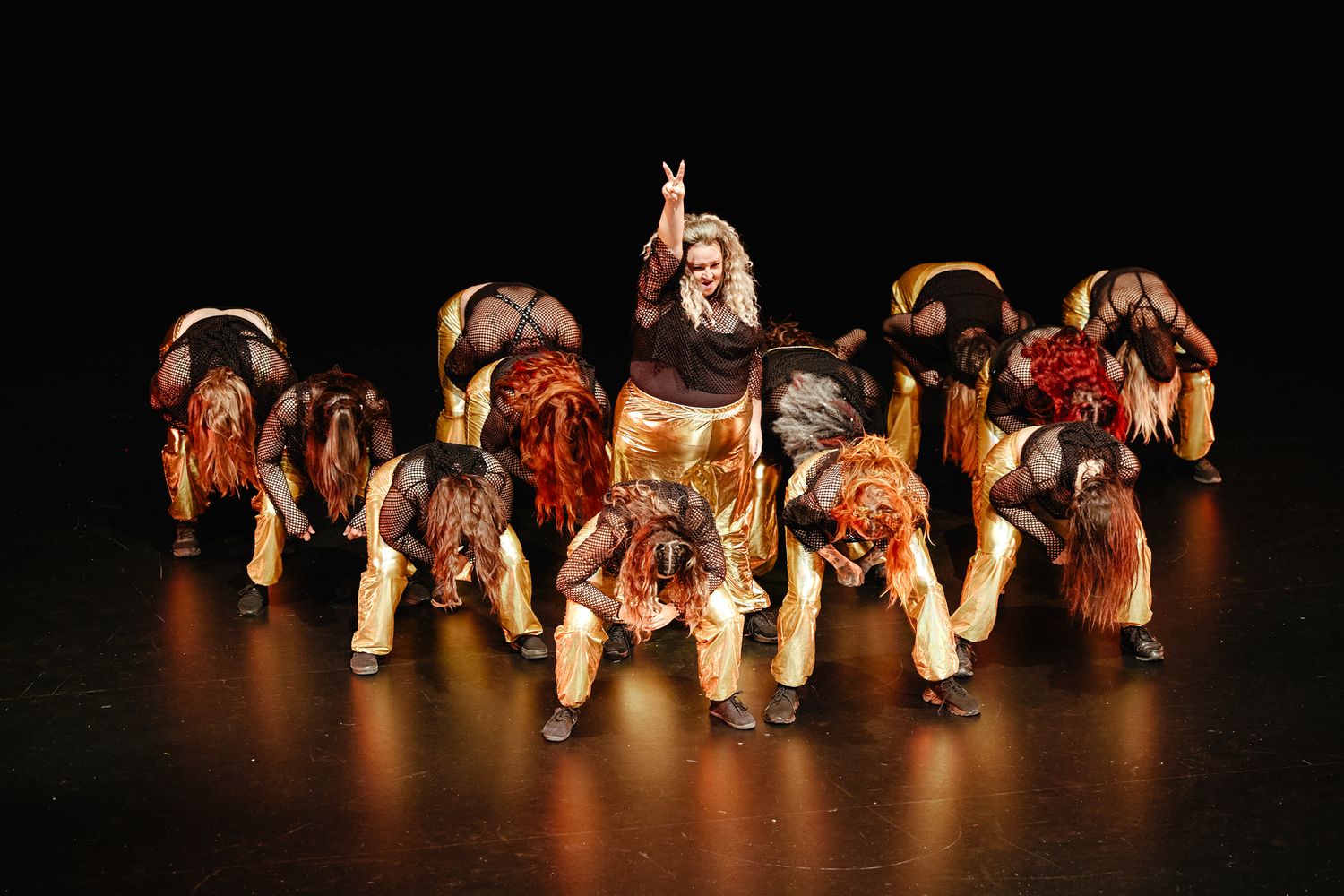 Traditional dancers perform a dynamic tribal group dance performance in colorful native costumes on a dark stage.