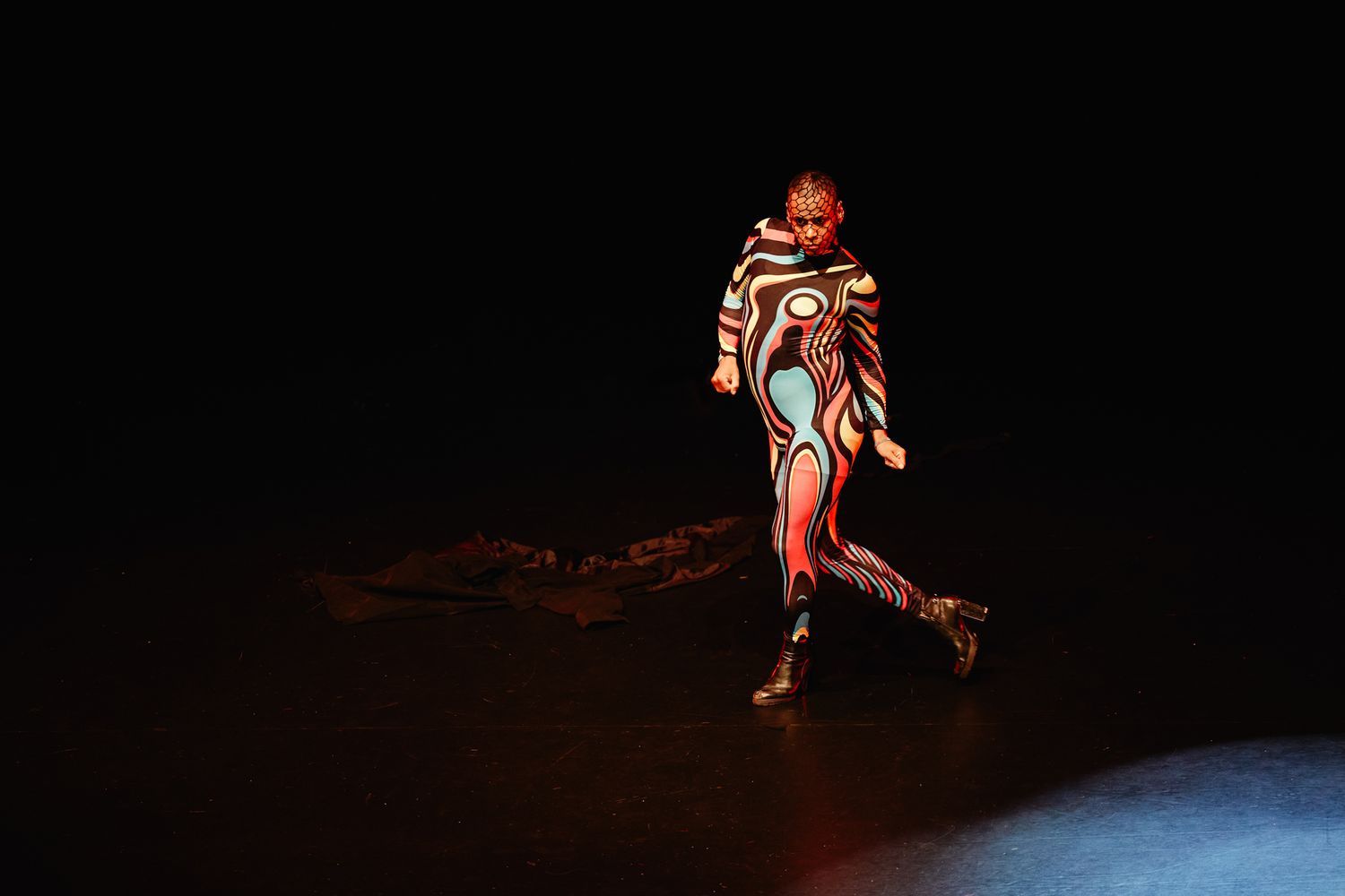 Six silhouetted dancers perform dramatic poses in stage lighting against a dark background.