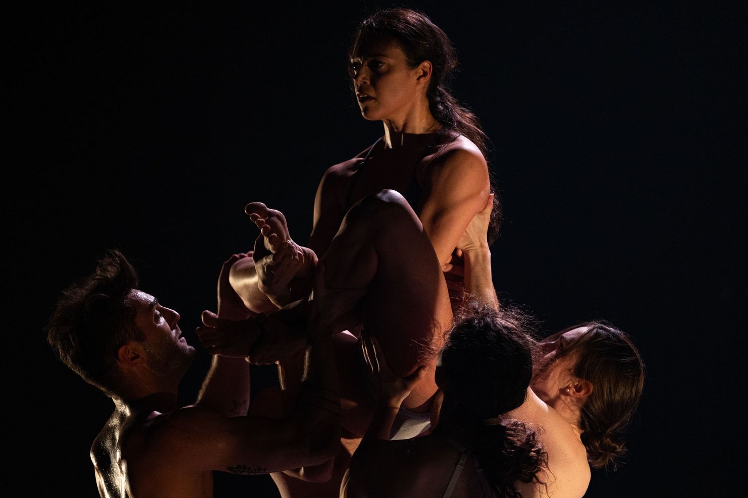 Tango dancers in silhouette perform an intimate dance sequence against a dark backdrop.