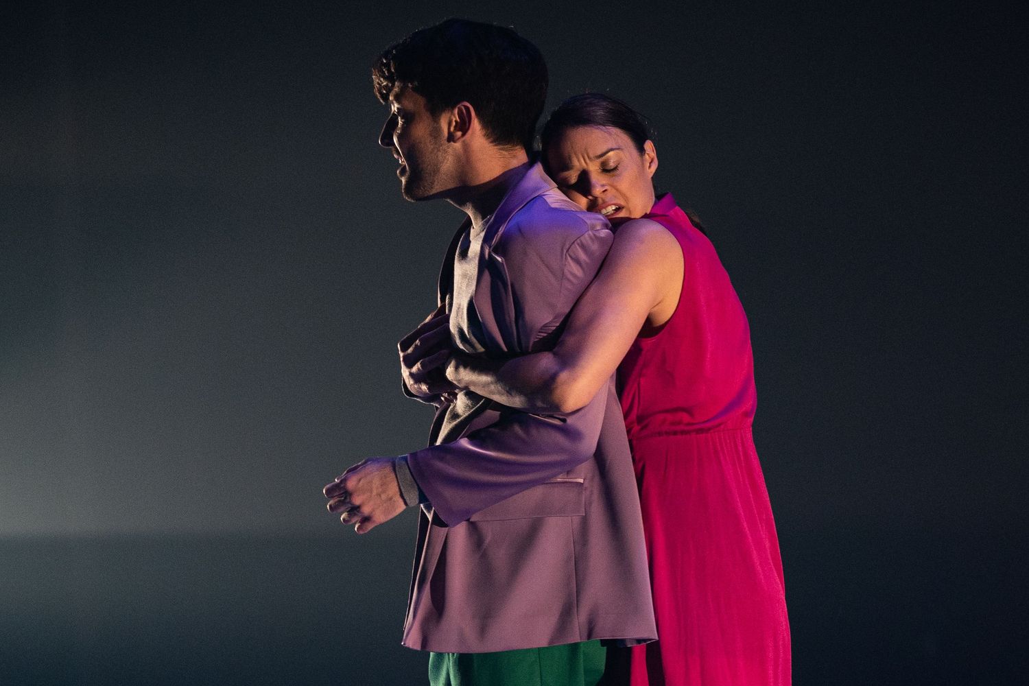 A couple embraces while dancing together in a dimly lit room.