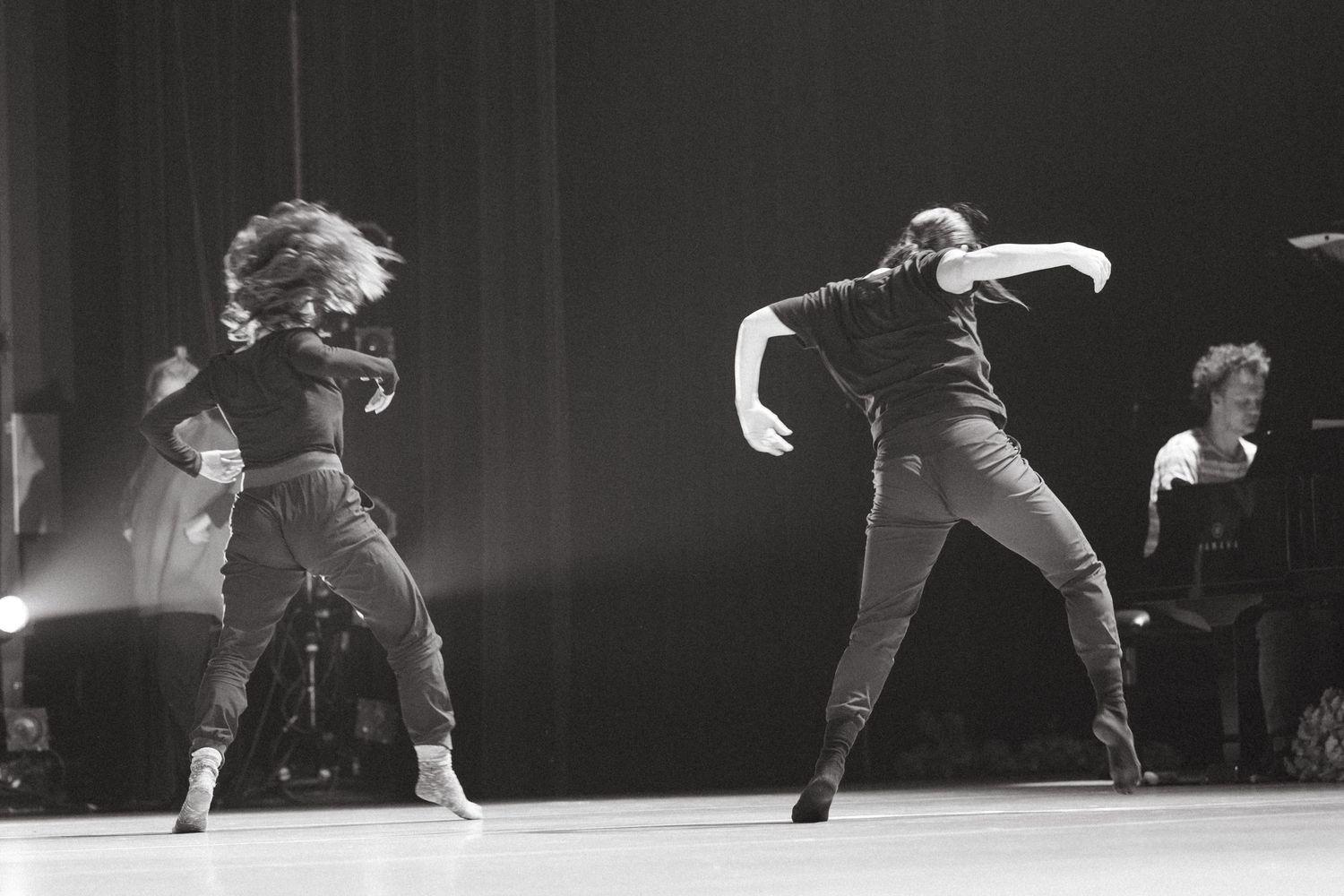 A series of dramatic black and white dance performance shots showing fluid movement across a dark stage.