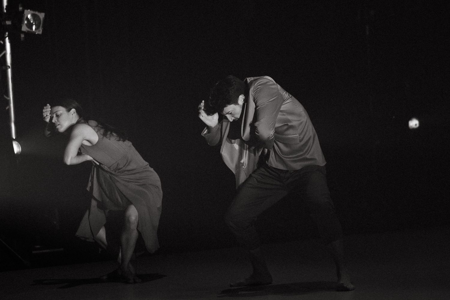 A cinematic series of black and white photographs showing dance movements in dark lighting on stage.