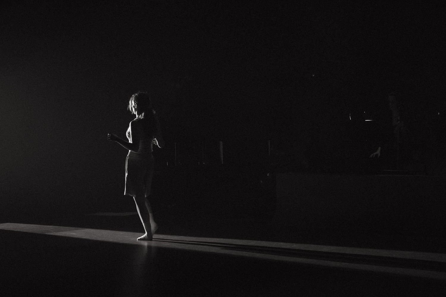 Silhouetted figure performs skilled stunts on a trampoline against a dark background.