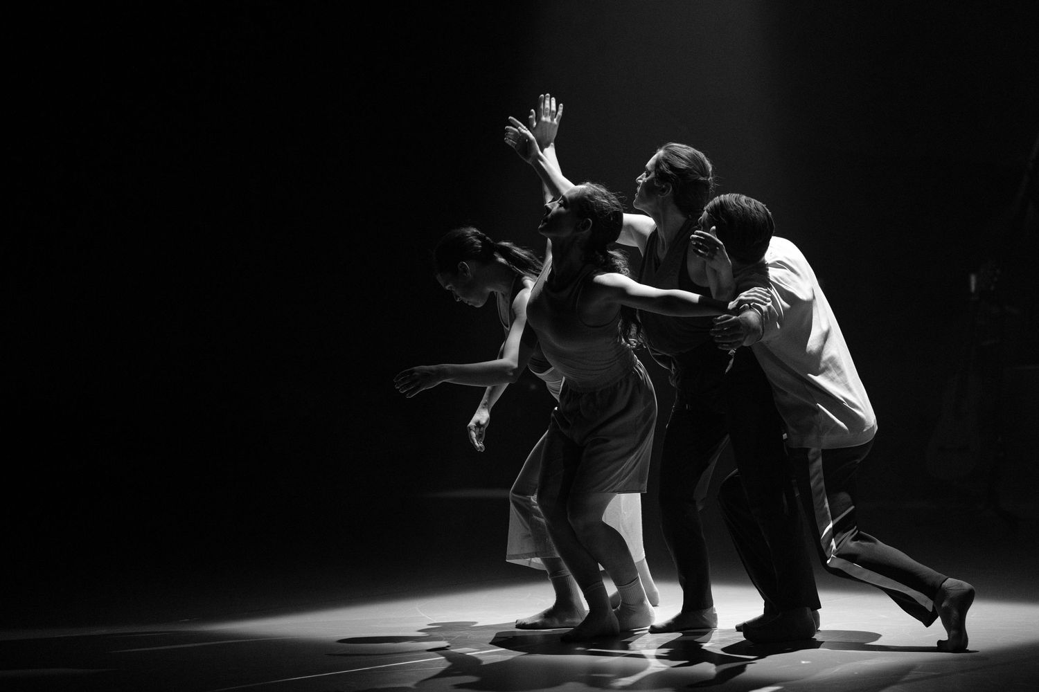 Seven black and white photographs show dancers in dramatic poses performing contemporary dance movements on stage.