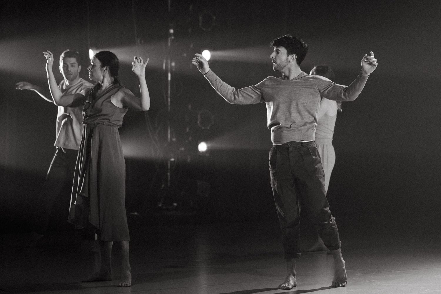 Sequence of six black and white images showing dance performers in expressive movement on a dark stage.