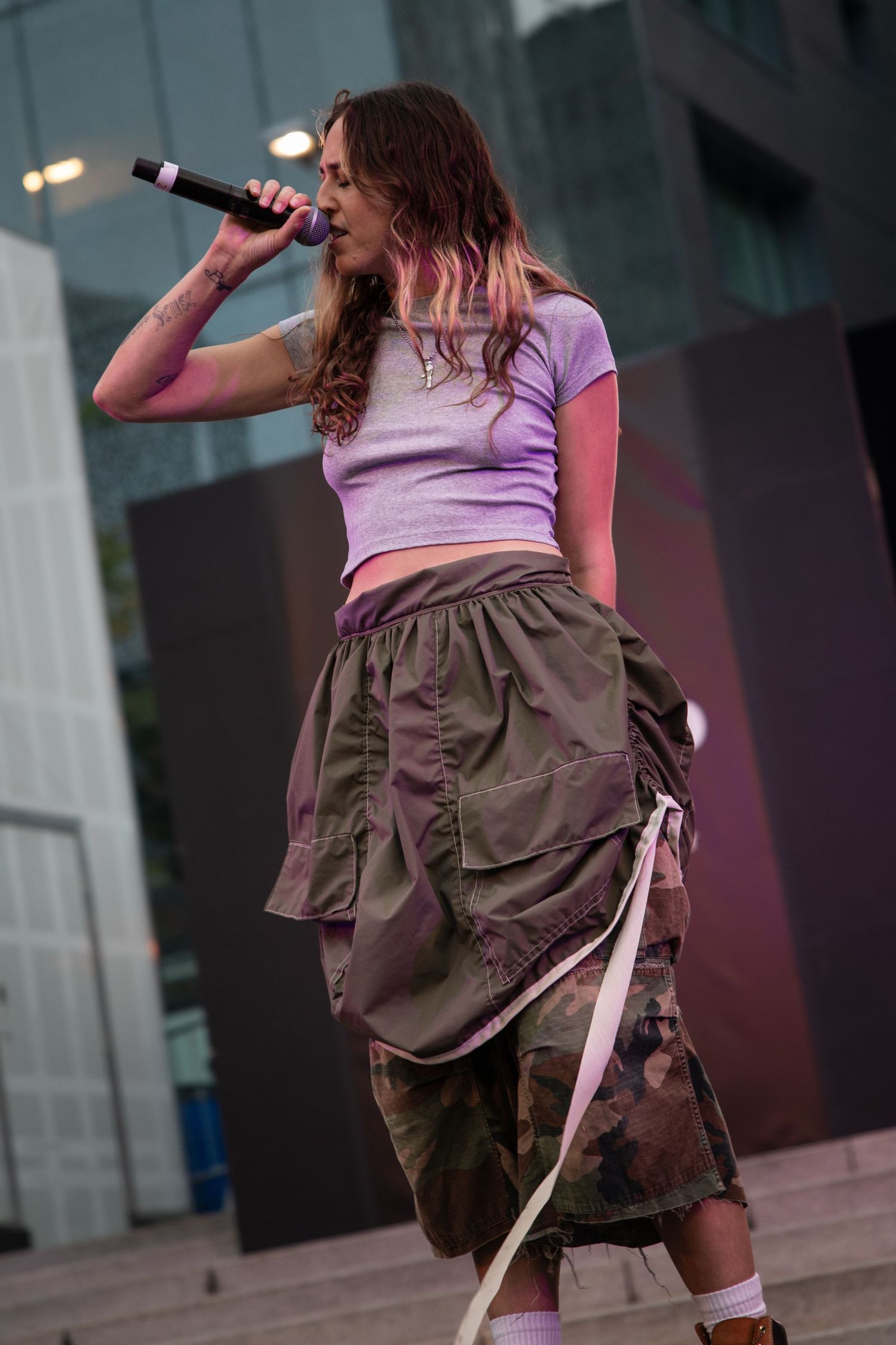 Multiple views of a performer on stage wearing an olive skirt and pink top during a dynamic dance routine.