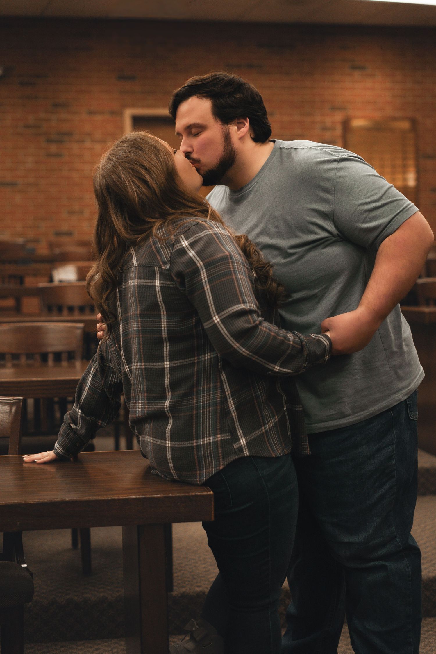 A romantic couple sharing an intimate moment in a rustic indoor setting with brick walls.