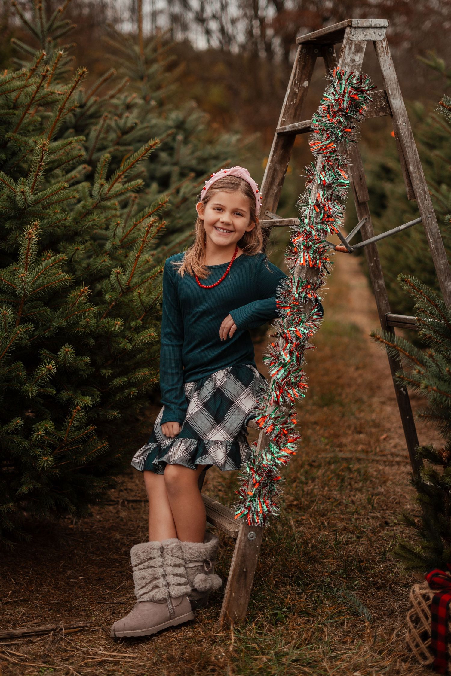 Holiday photo session at Christmas tree farm with festive decorations and greenery.