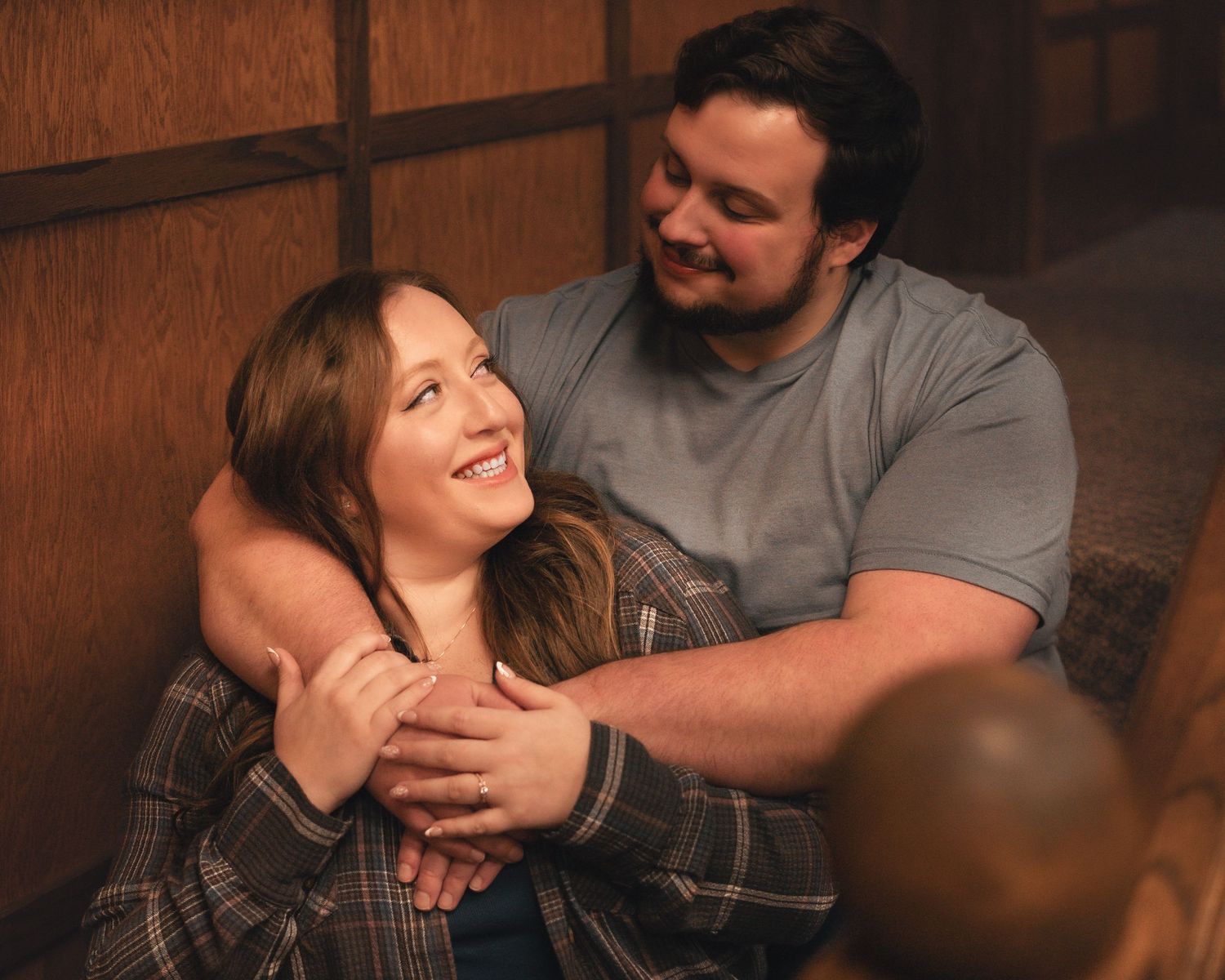 A couple sharing a joyful embrace while sitting together in a cozy indoor setting.